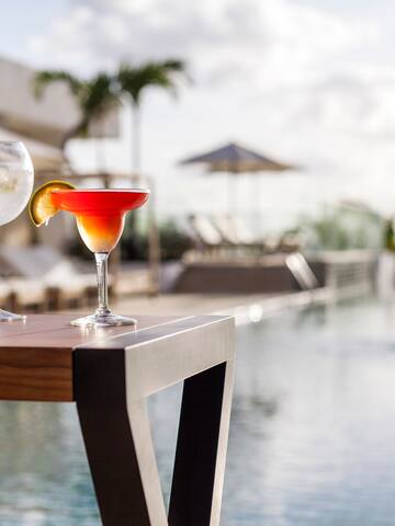 two glasses of drinks on a table by a pool