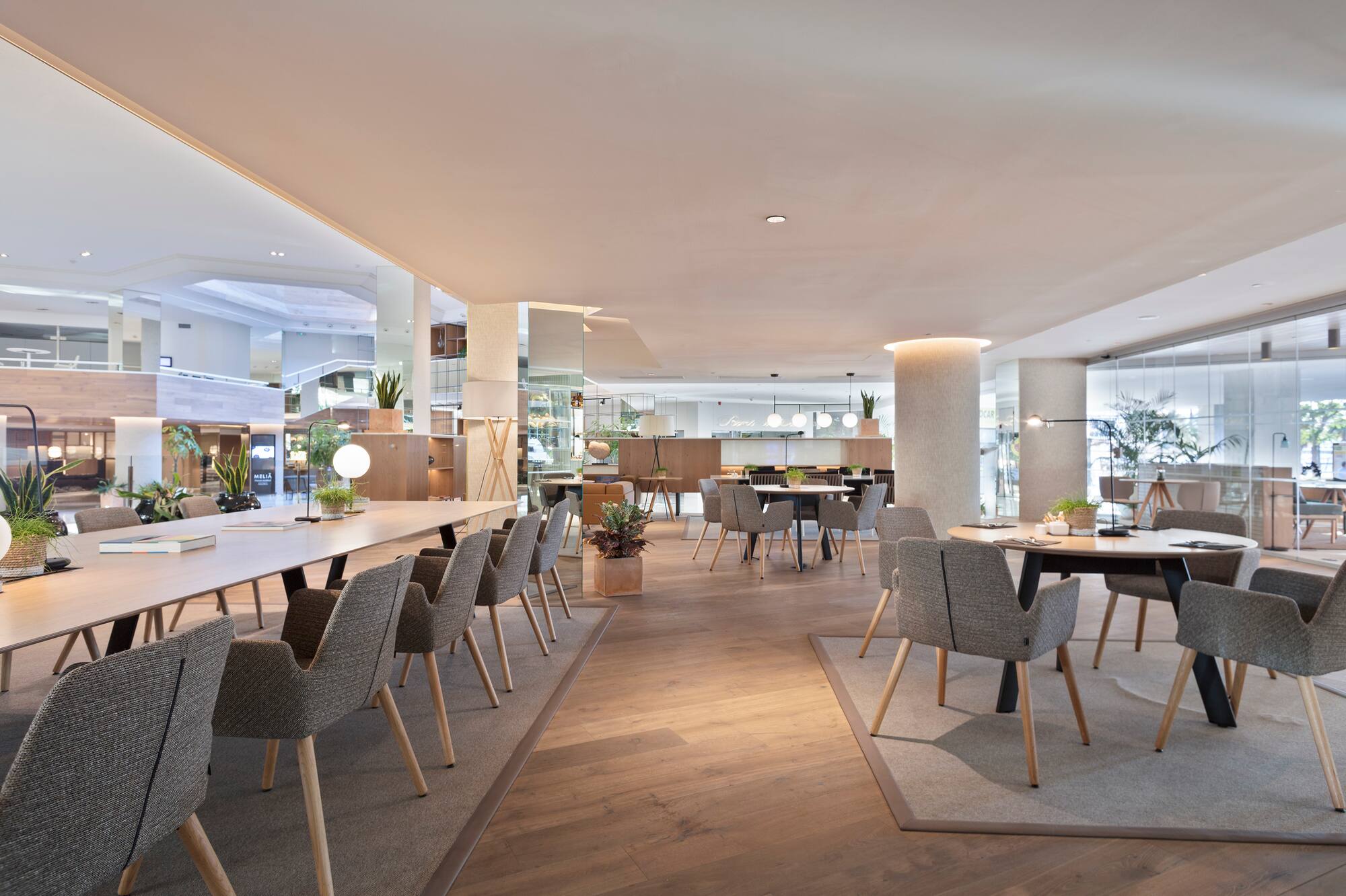 Bright, modern hotel lounge with long communal table and diverse seating.