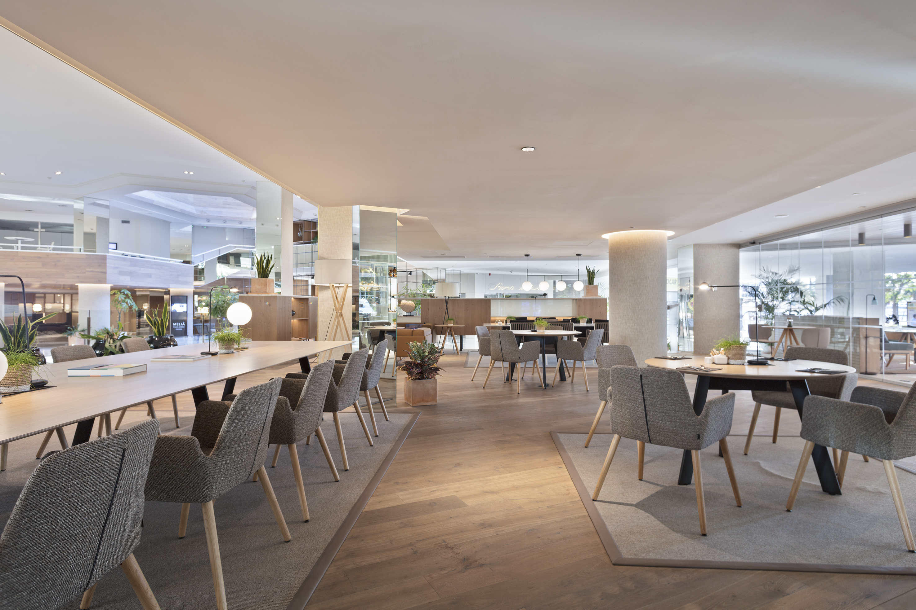 Bright, modern hotel lounge with long communal table and diverse seating.