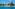 Modern beachfront resort, busy sandy beach, clear blue ocean.