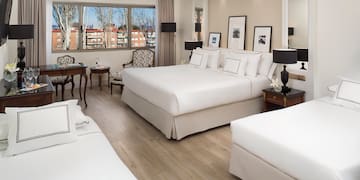 a room with white beds and a wood floor
