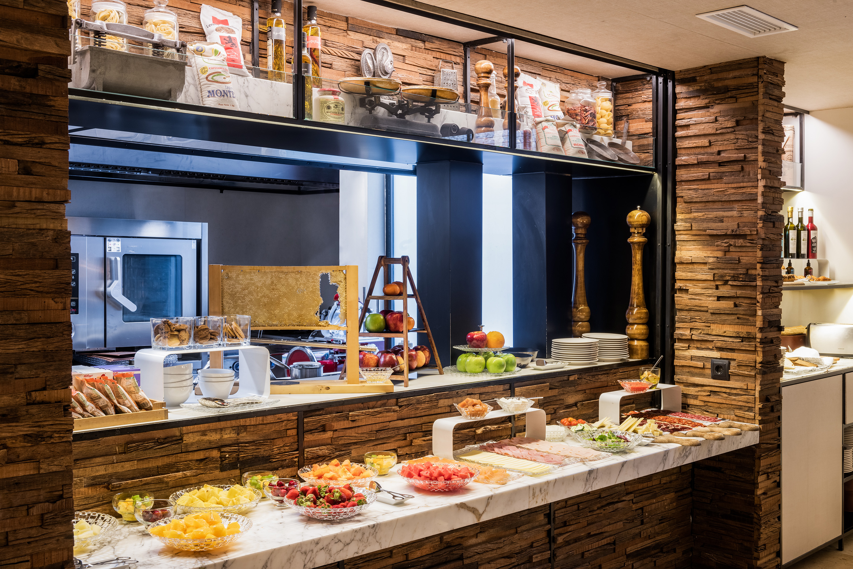 Hotel breakfast buffet with fresh fruit, cold cuts, pastries, and honeycomb.