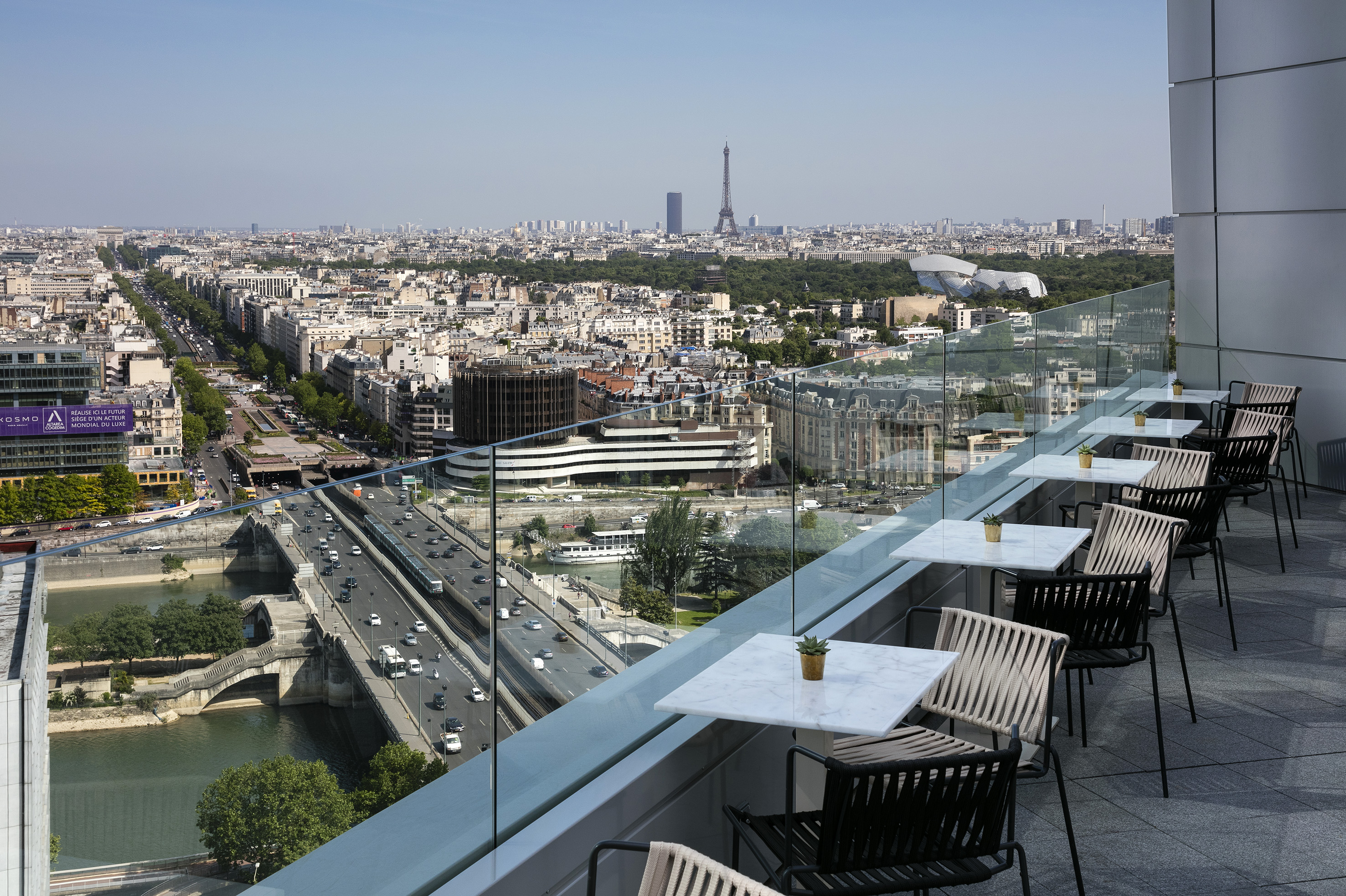 Modern rooftop terrace with Parisian cityscape, Eiffel Tower, and Seine River.