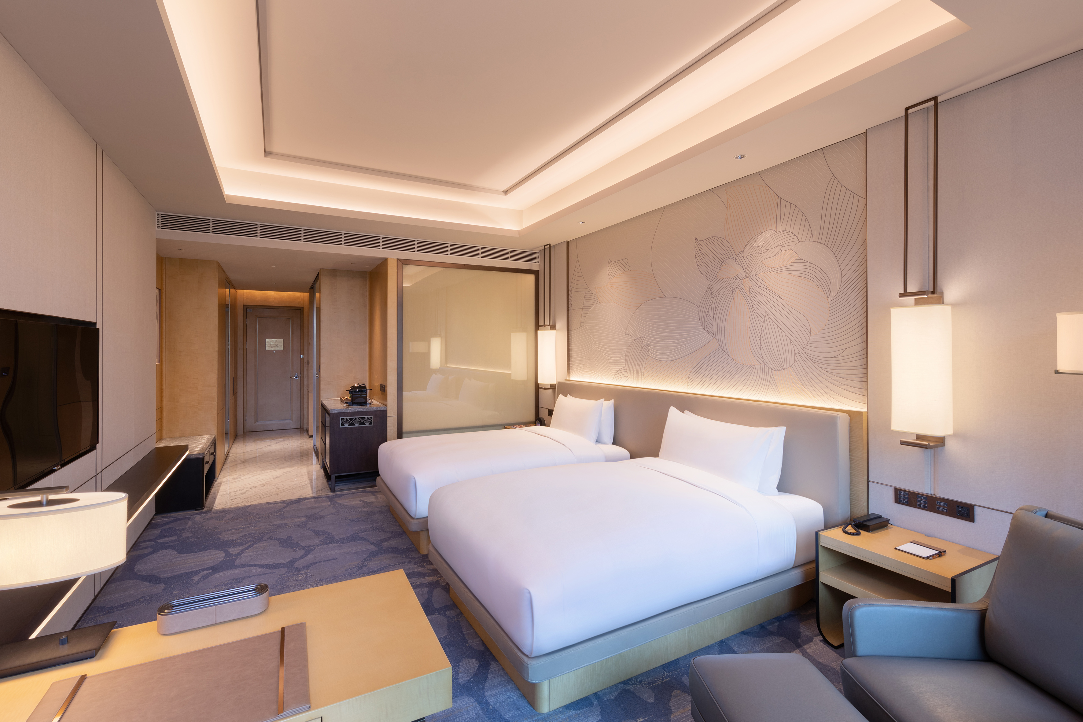 Contemporary hotel room with two double beds, elegant design, and muted tones.