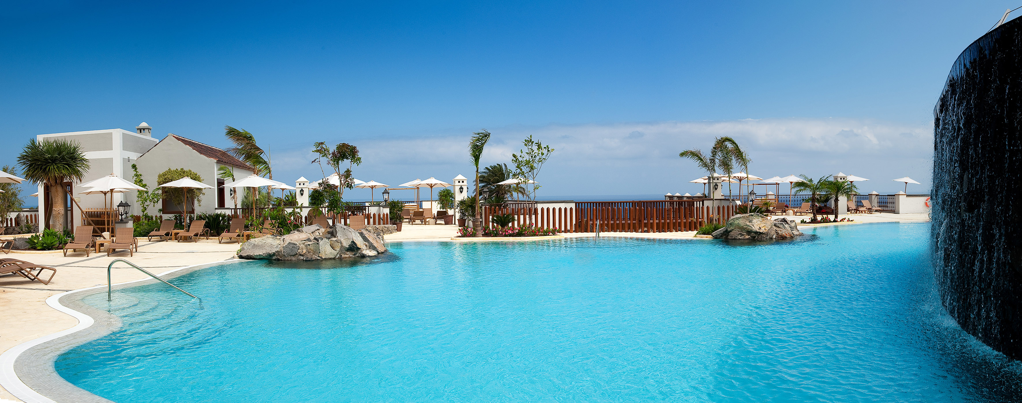 a pool with a fence and umbrellas