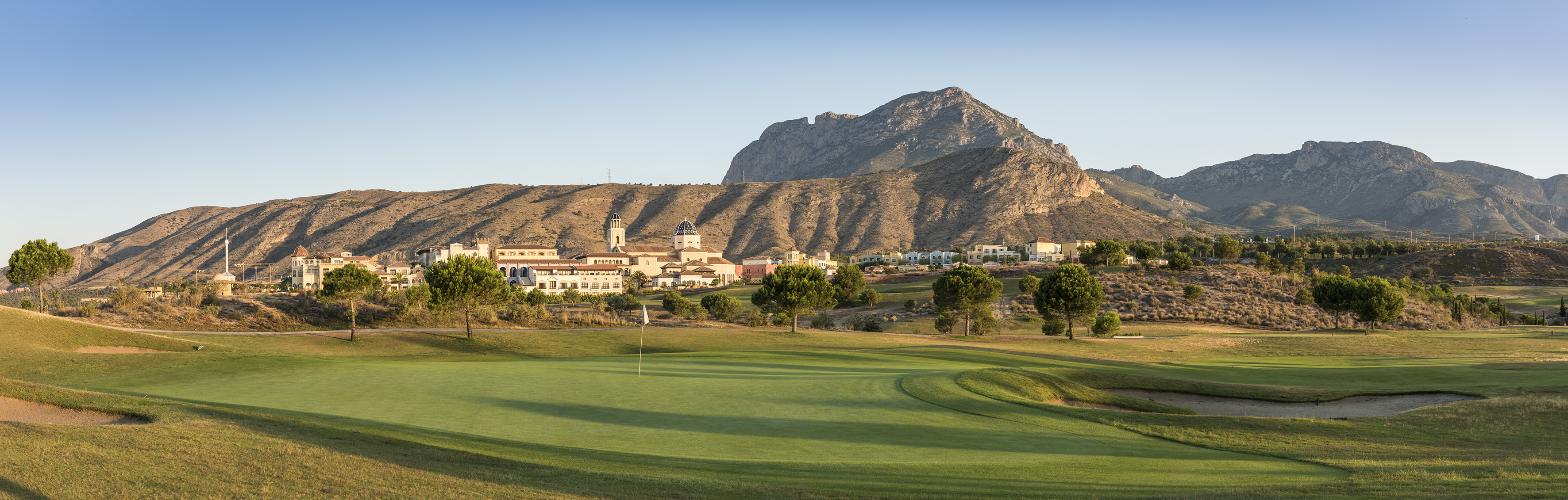 Mediterranean golf resort with village architecture and rugged mountains.