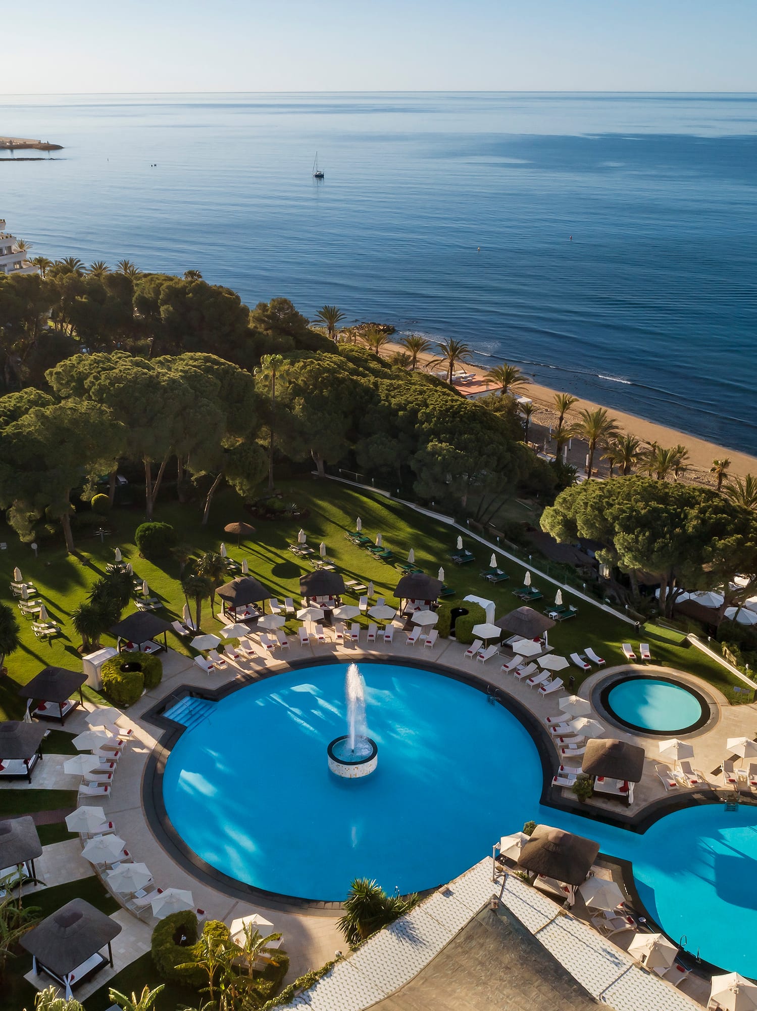 a pool with a fountain in the middle of a resort