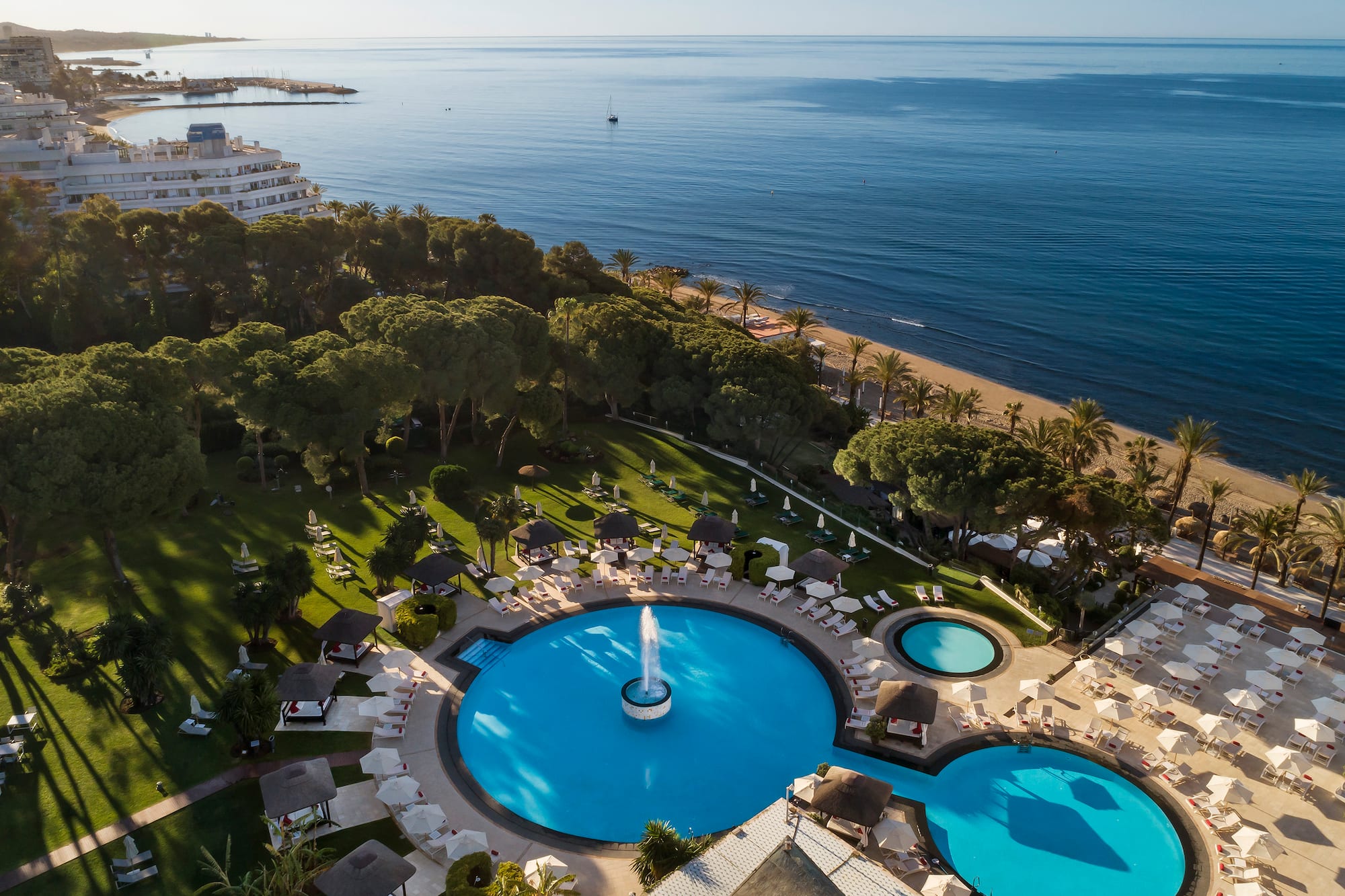 a pool with a fountain in the middle of a resort