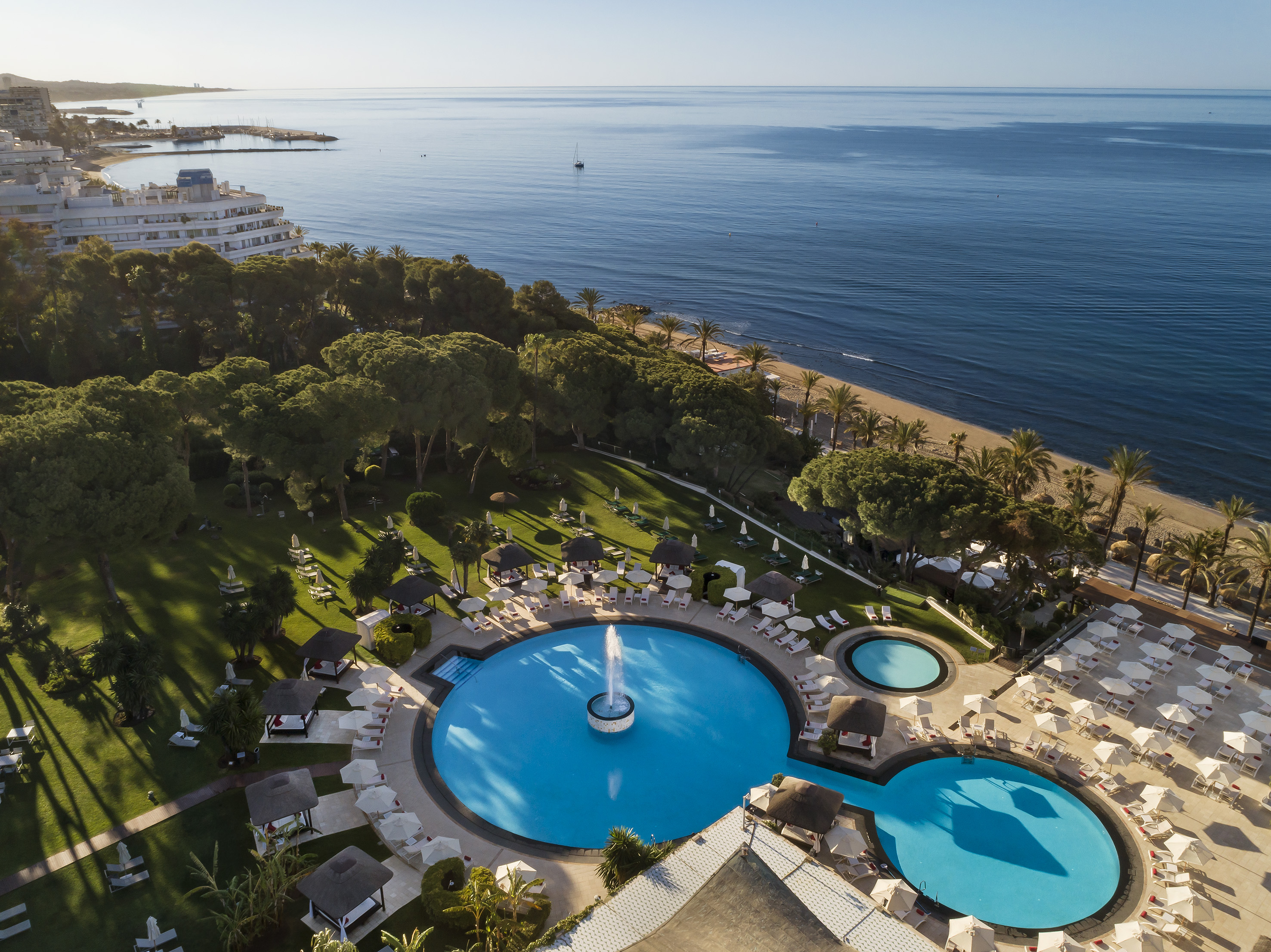 a pool with a fountain in the middle of a resort