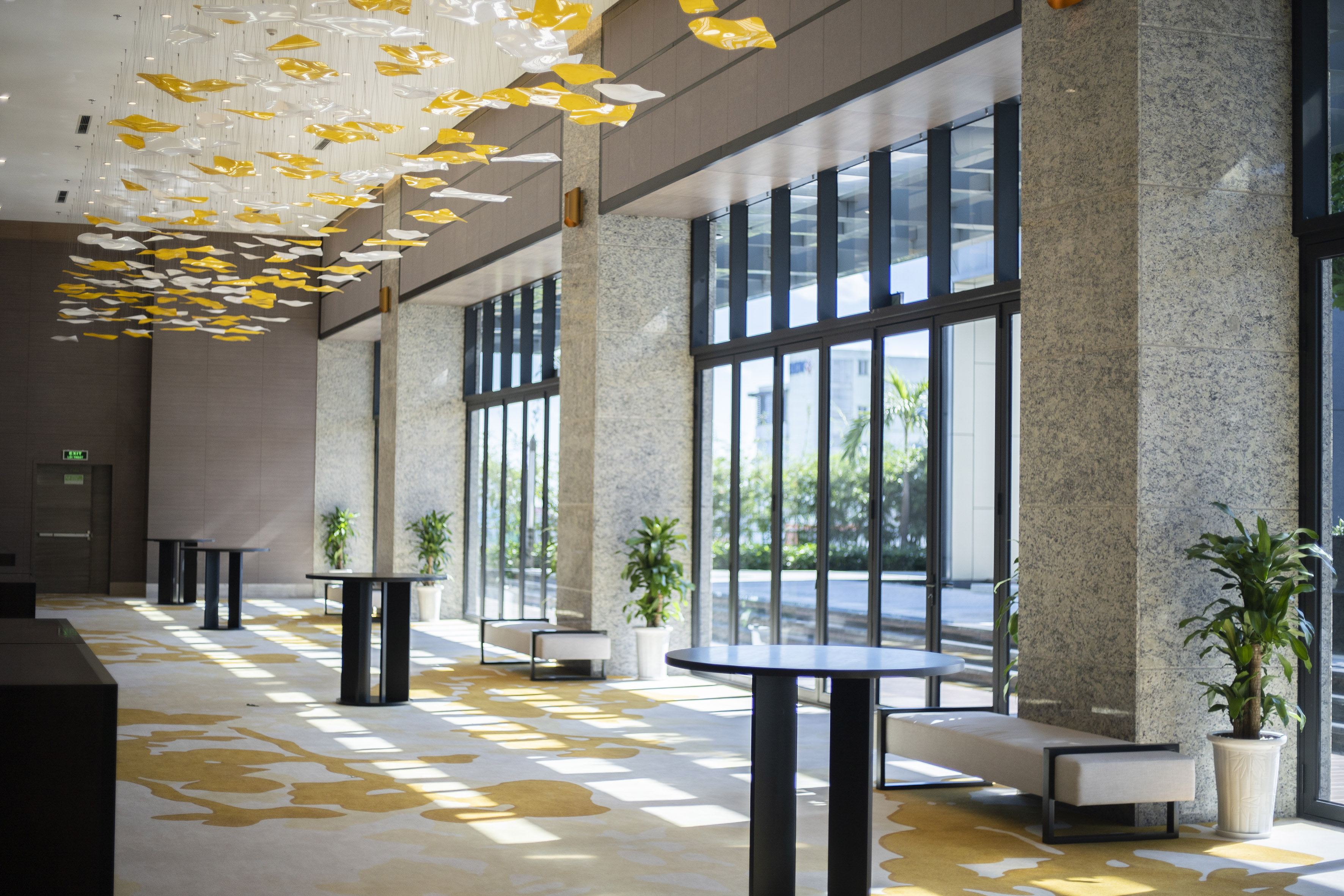 Contemporary event space with yellow chandelier, natural light, and high-top tables. - Grand Ballroom - Meliá Vinpearl Thanh Hoa, Thanh Hoa
