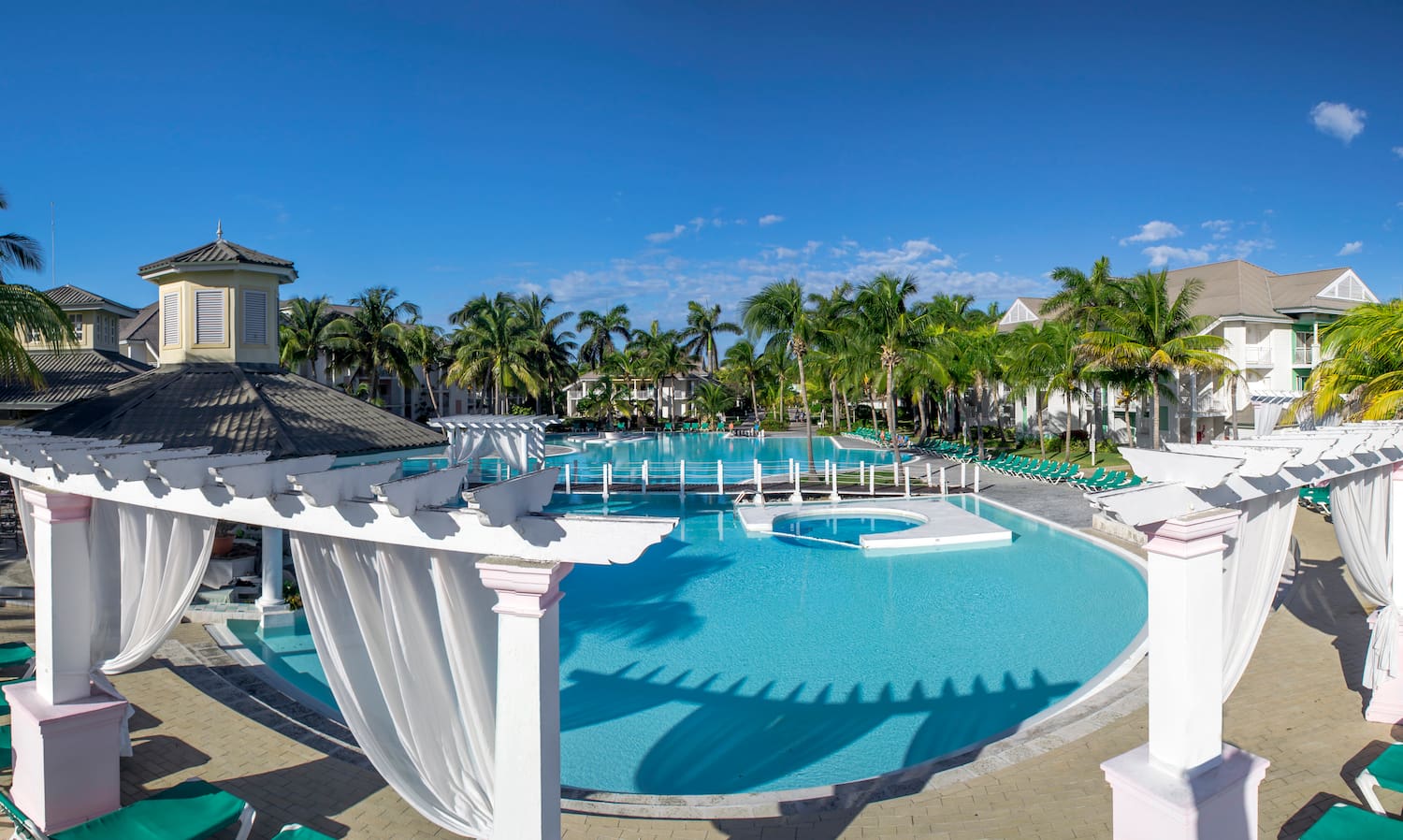 a pool with palm trees and a gazebo