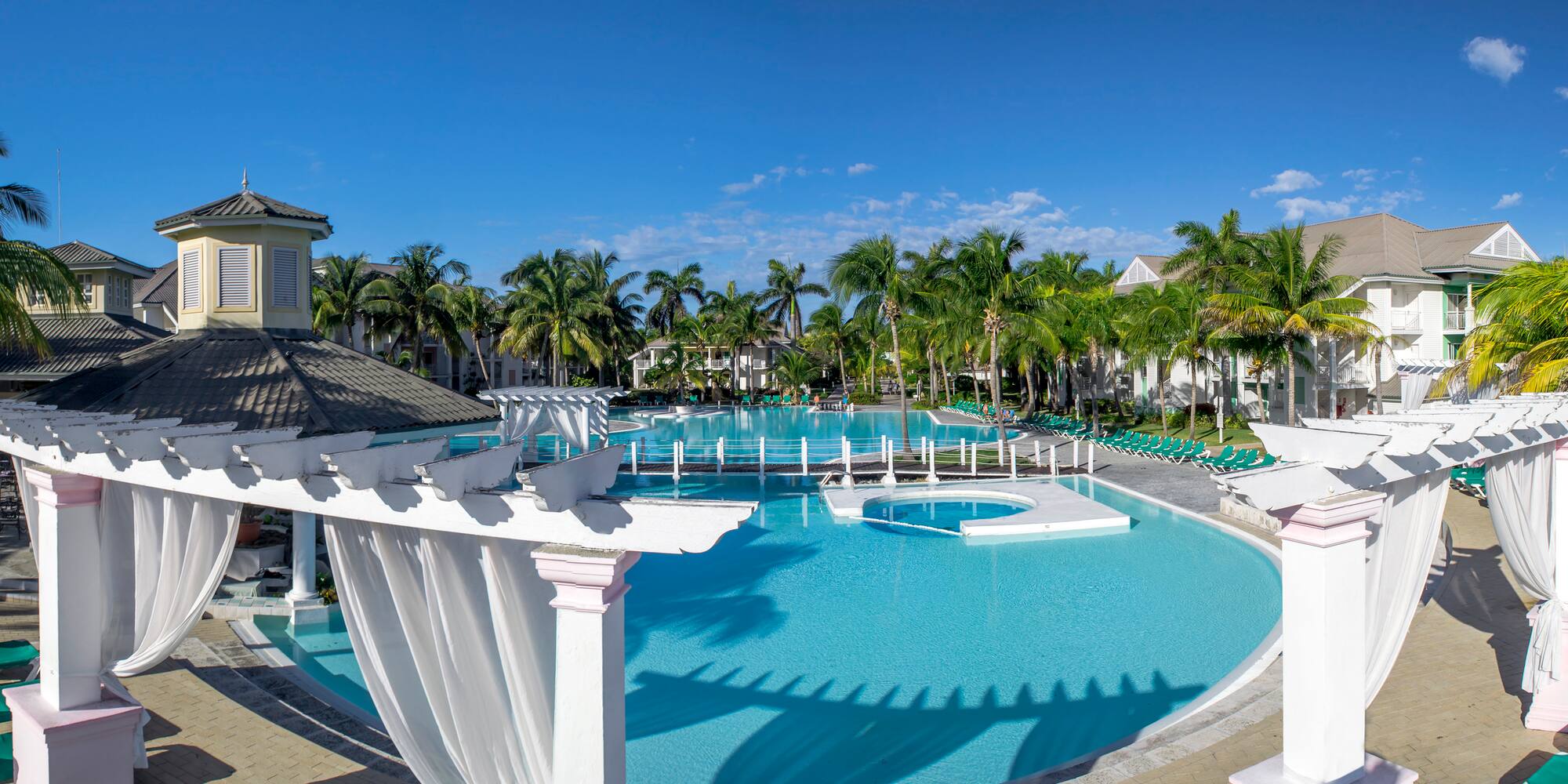 a pool with palm trees and a gazebo