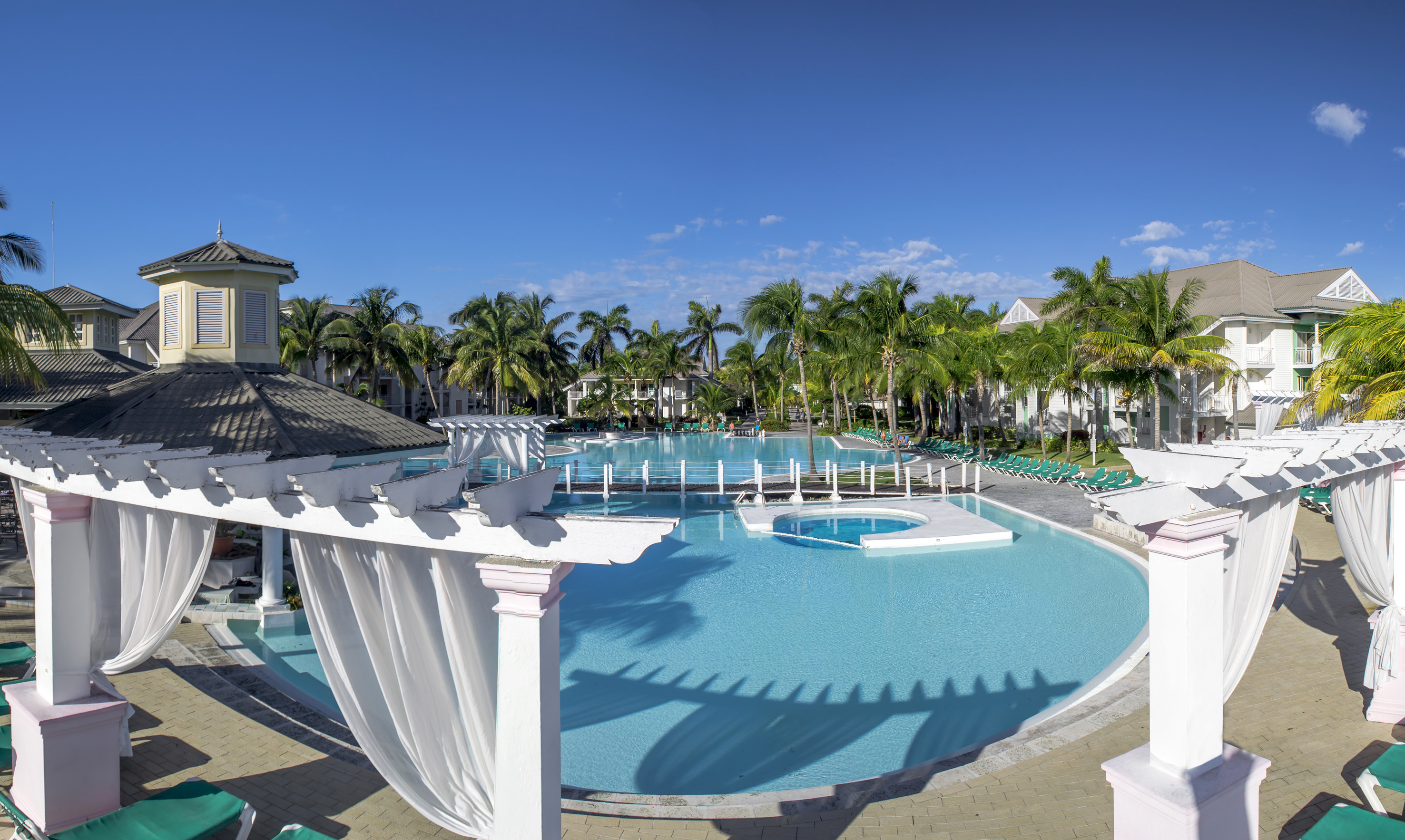 a pool with palm trees and a gazebo