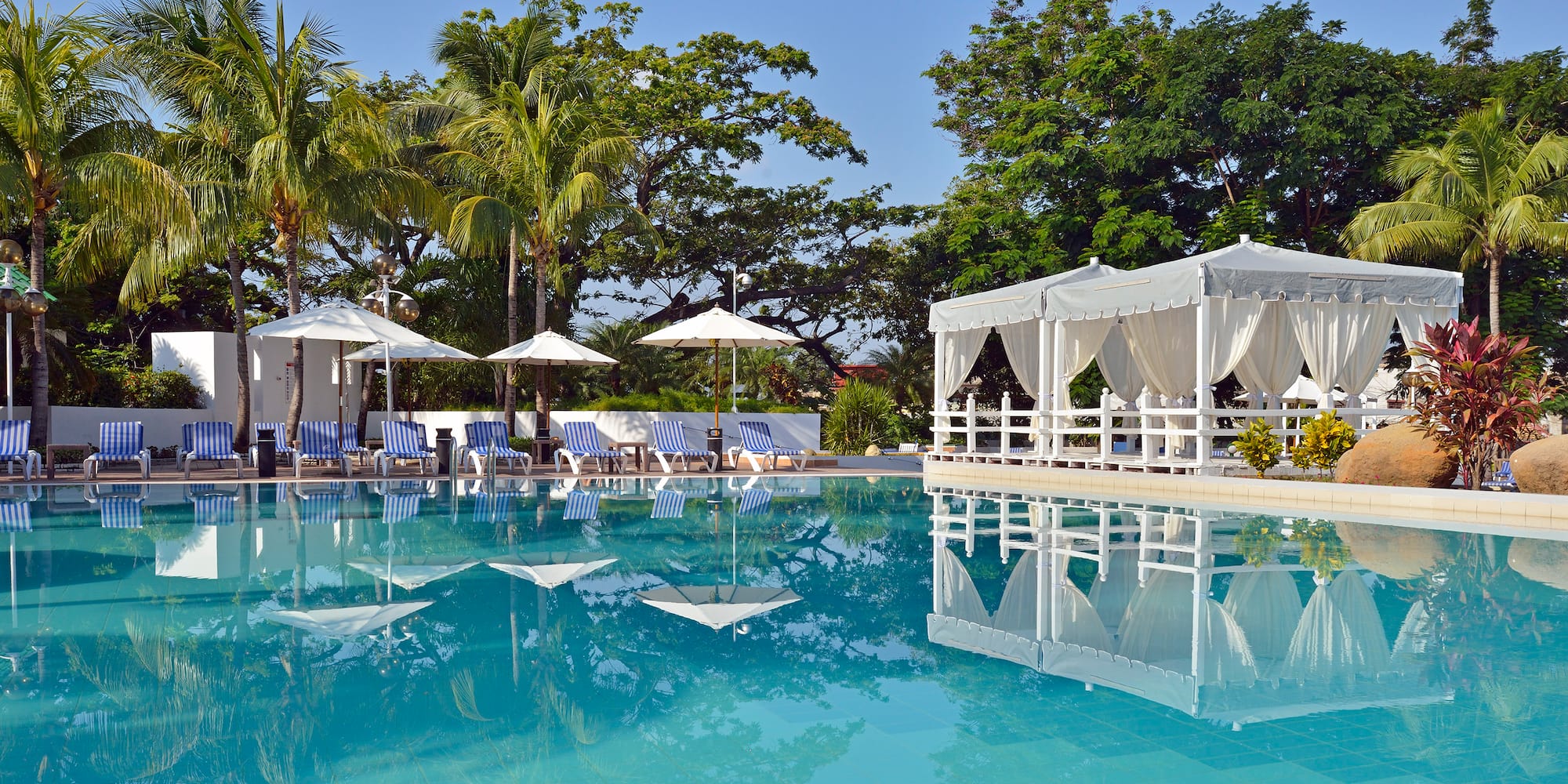 a pool with white awnings and umbrellas