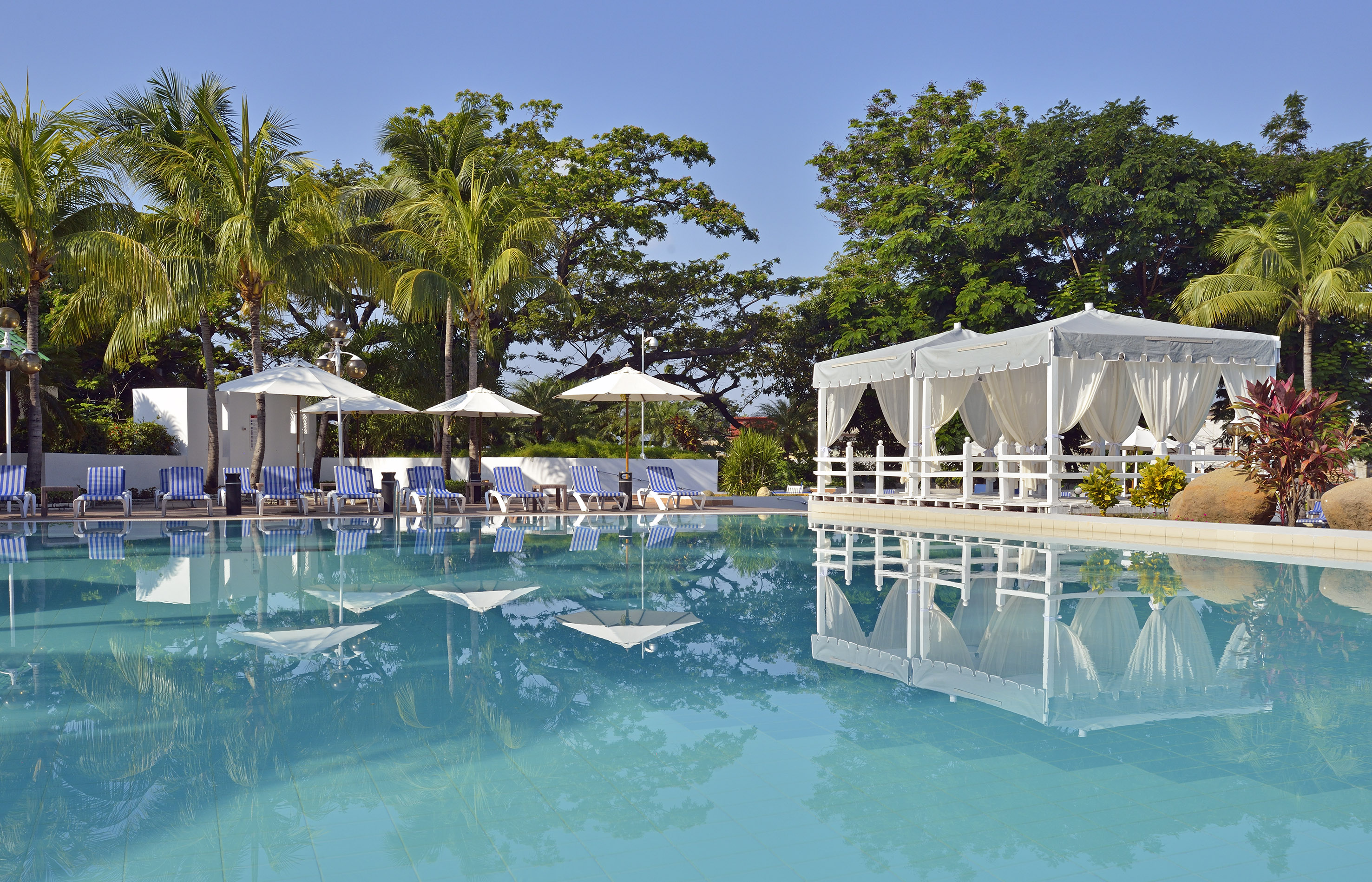 a pool with white awnings and umbrellas