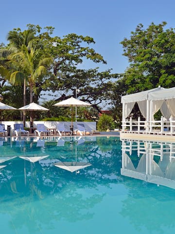 a pool with white awnings and umbrellas