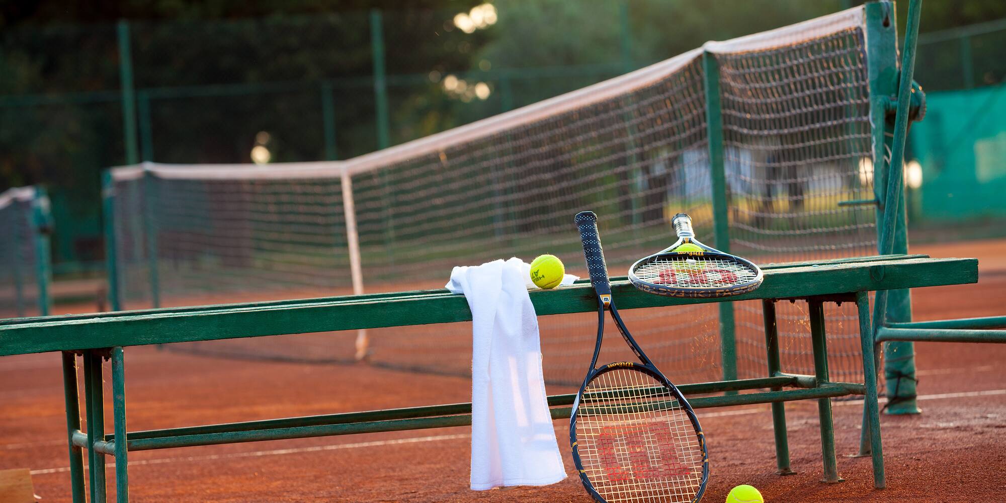 a tennis rackets and balls on a bench