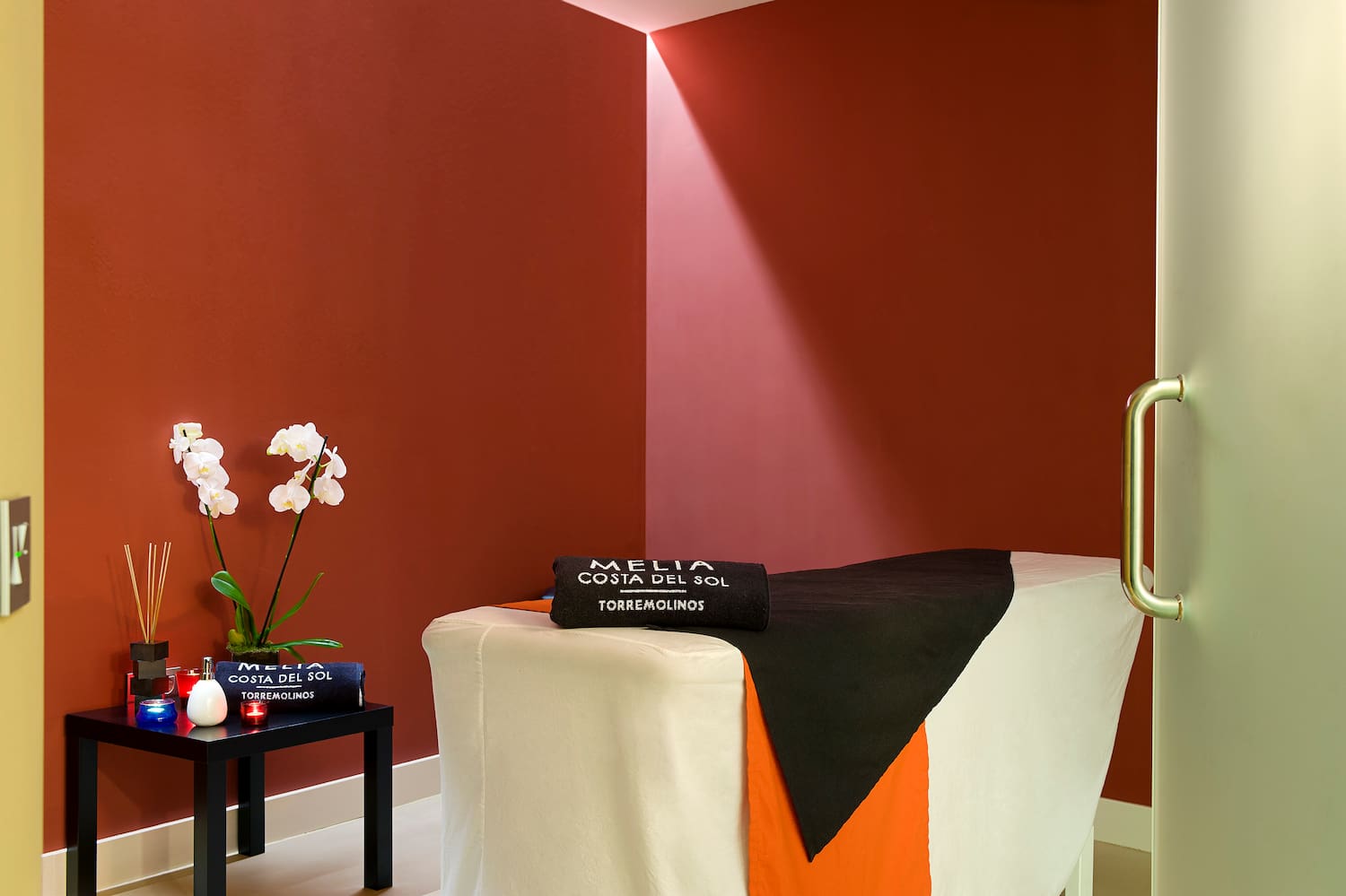 a massage table with a black towel and white and orange cloth