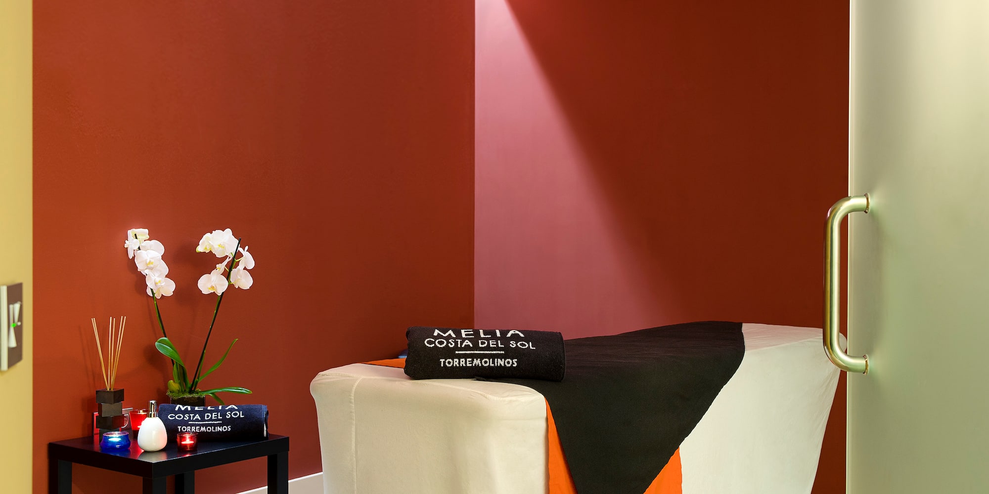 a massage table with a black towel and white and orange cloth