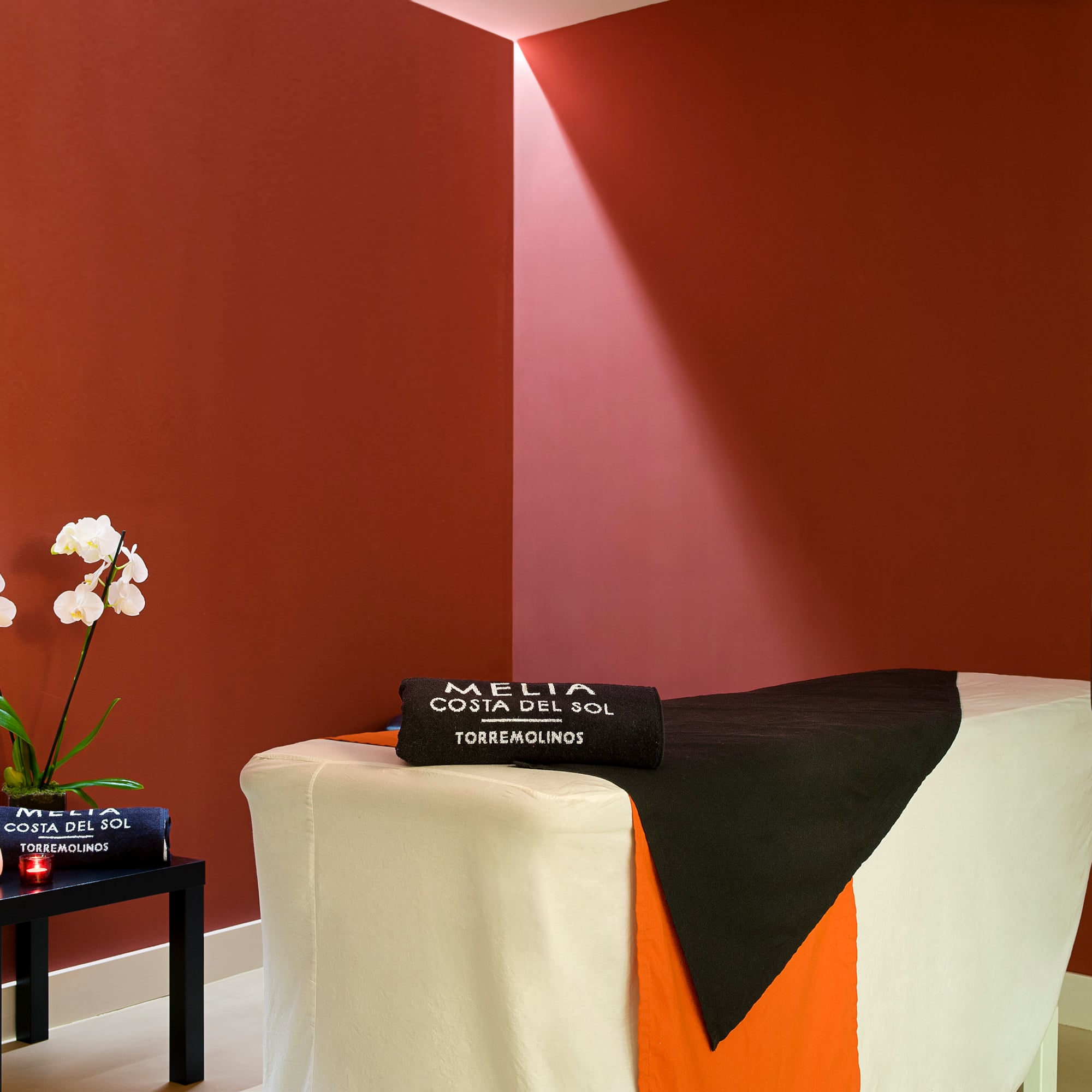 a massage table with a black towel and white and orange cloth