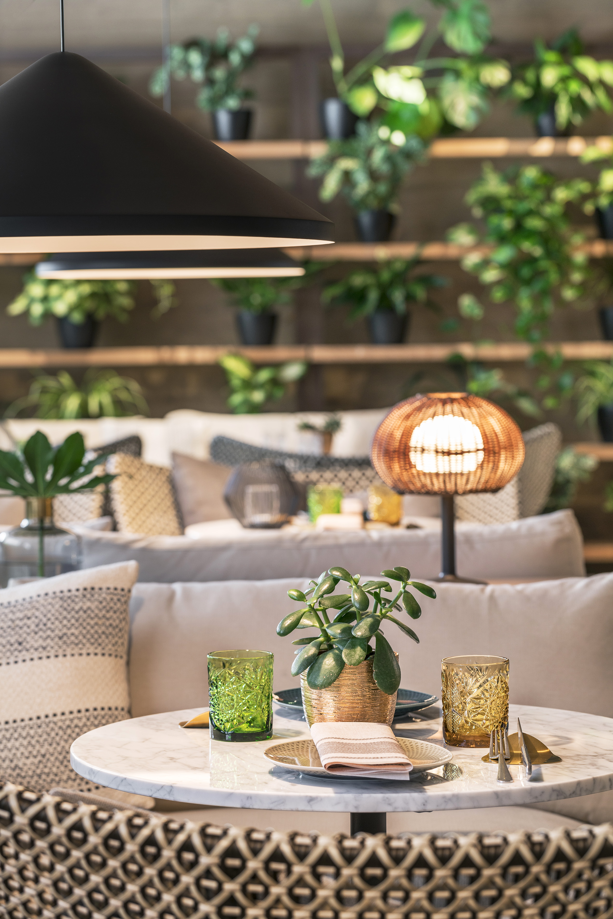 Modern dining with marble table, potted plant, and green plant wall decor.