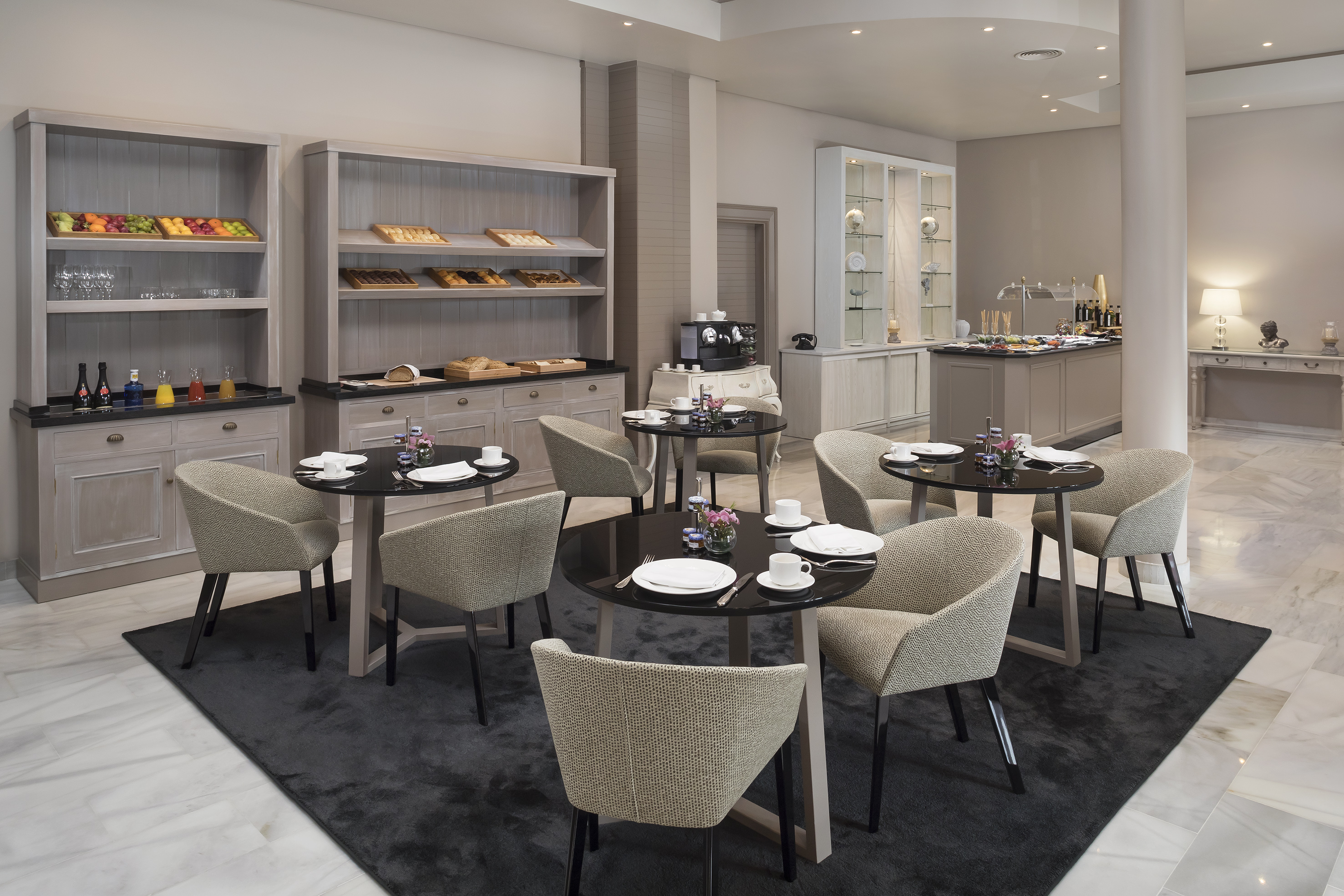 Elegant hotel breakfast room with buffet, fruit, and modern dining tables.