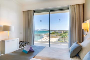 a bedroom with a view of the beach and a large window