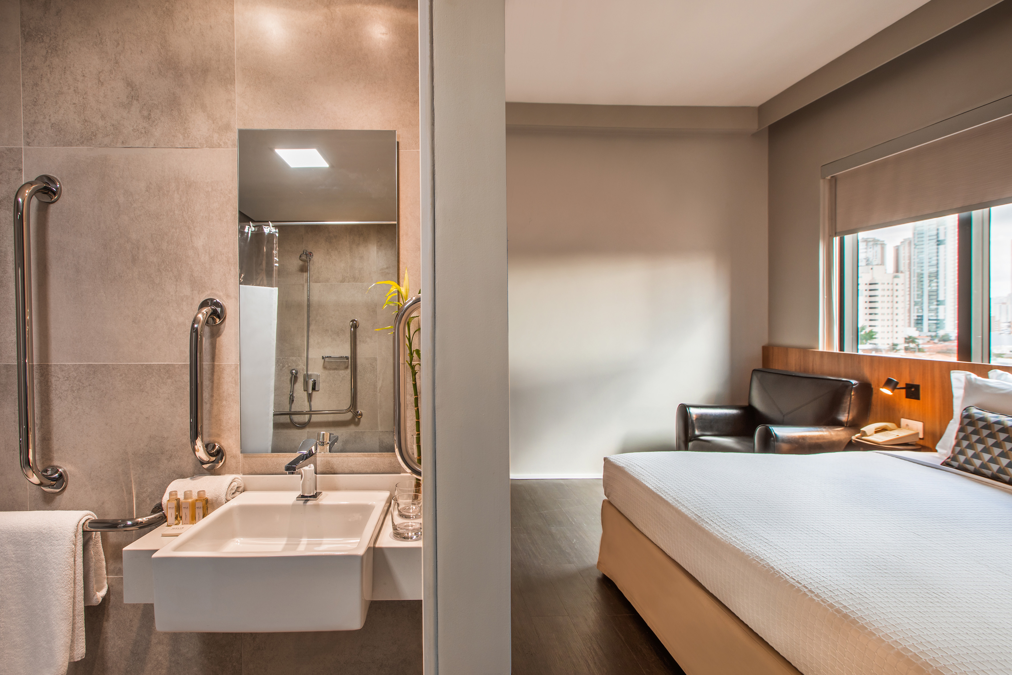Accessible hotel room with modern bathroom, comfortable bed, and city view.