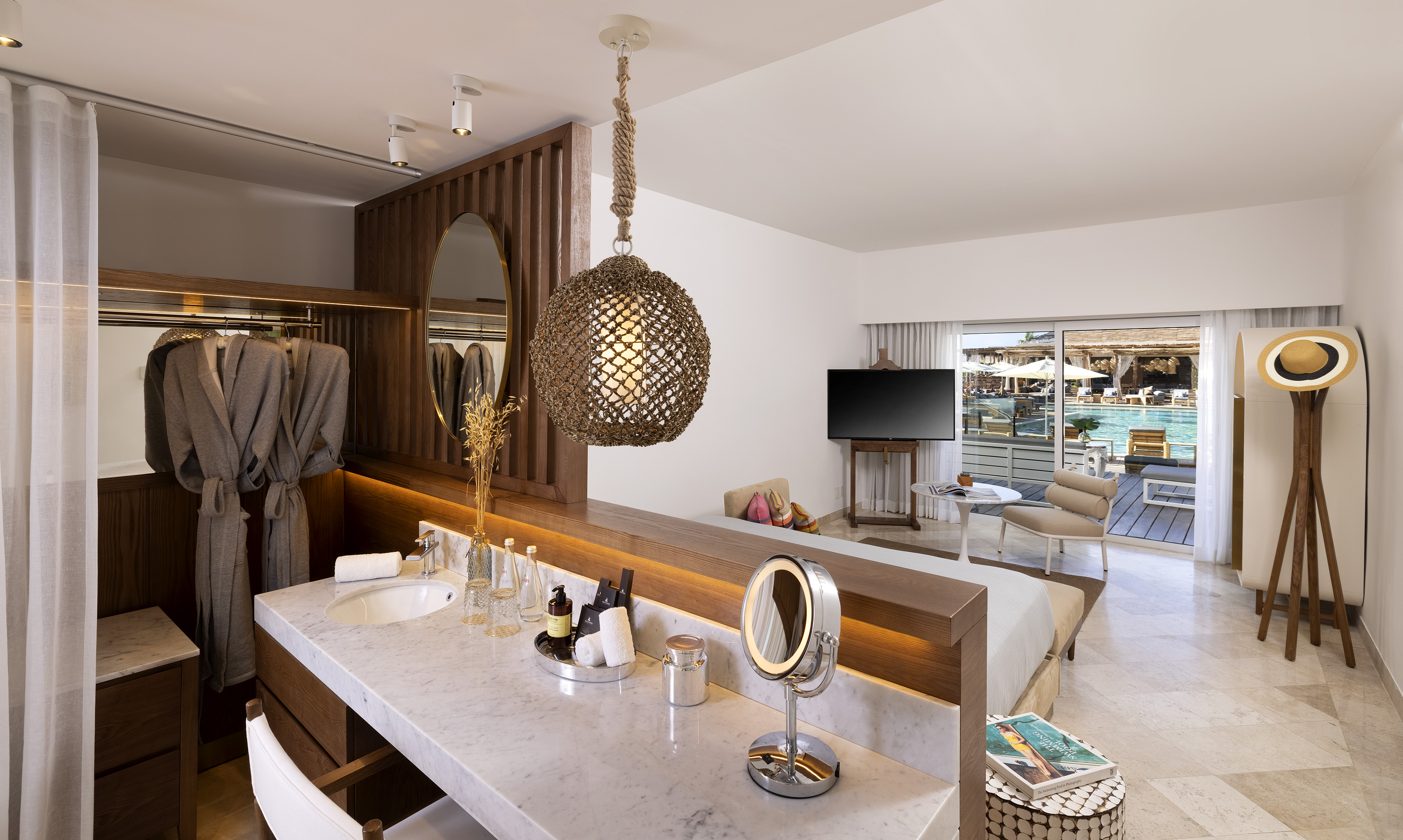 Modern resort suite with open bathroom, marble vanity, and direct pool view.