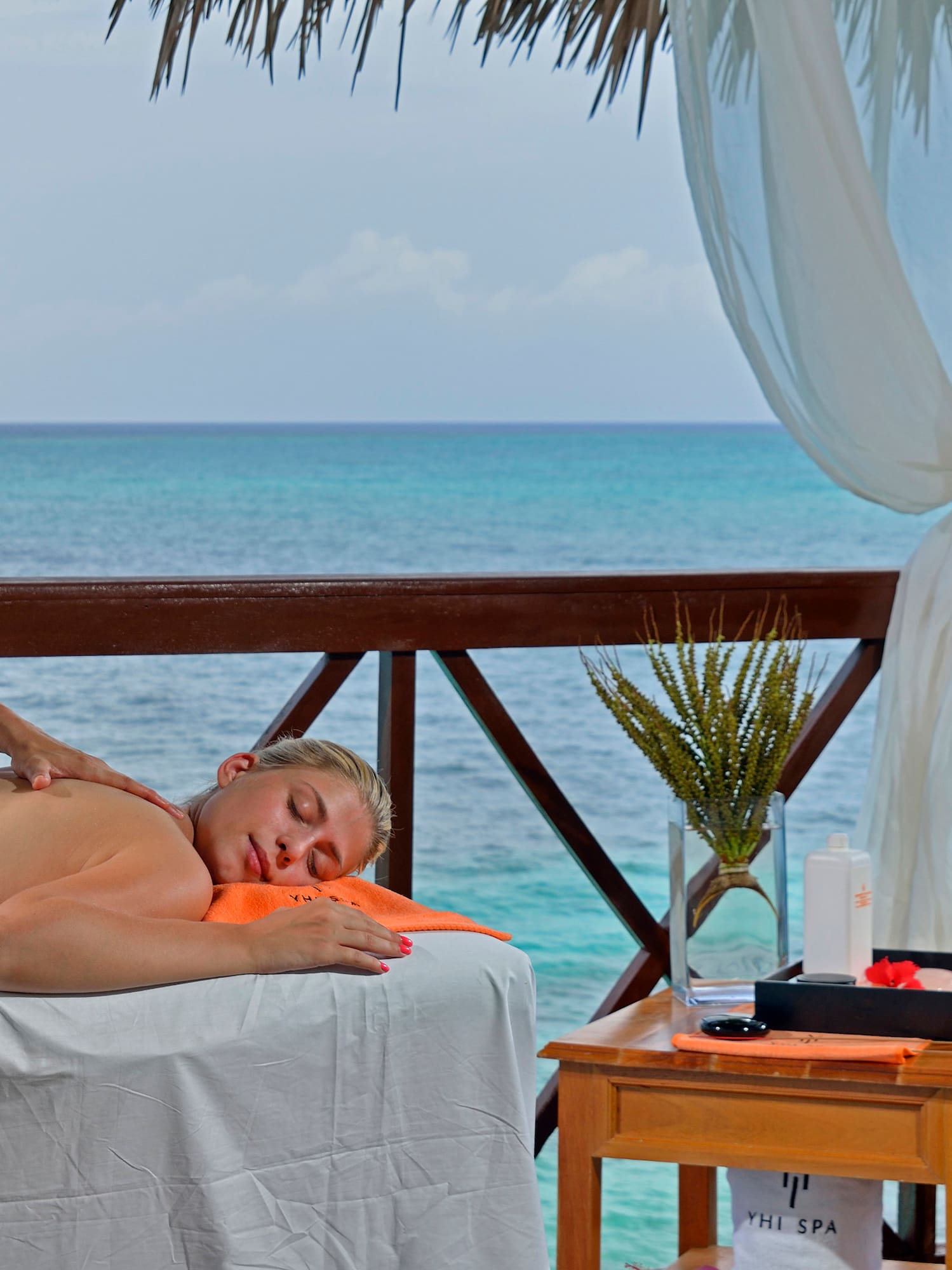 a woman lying on a table with a body of water behind her