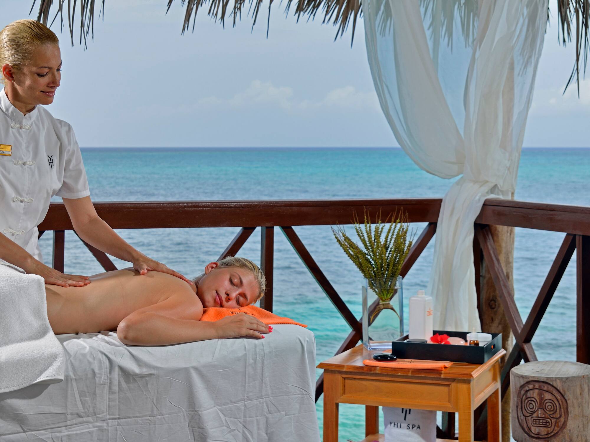 a woman lying on a table with a body of water behind her