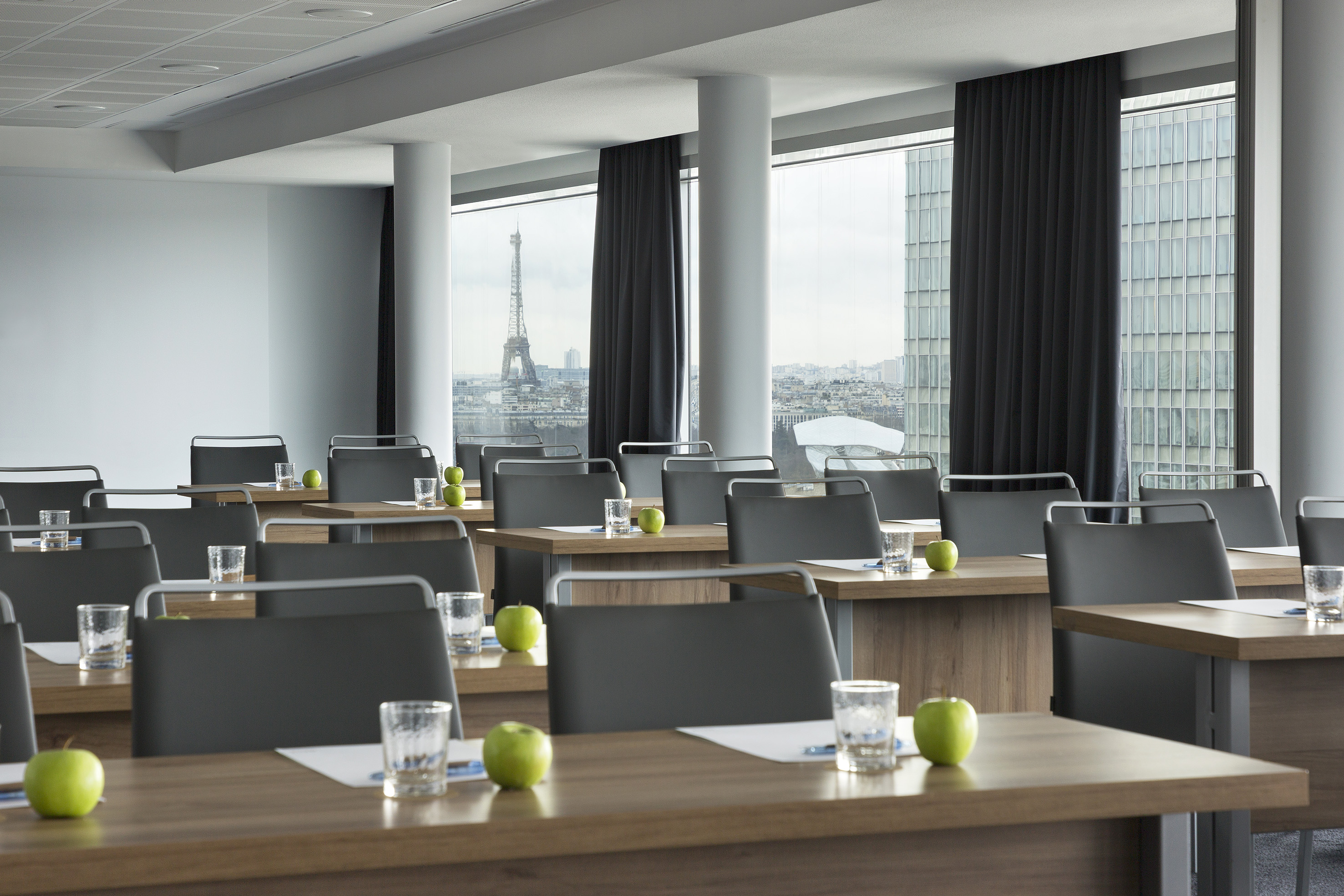 Modern conference room with Eiffel Tower view, green apples on tables.