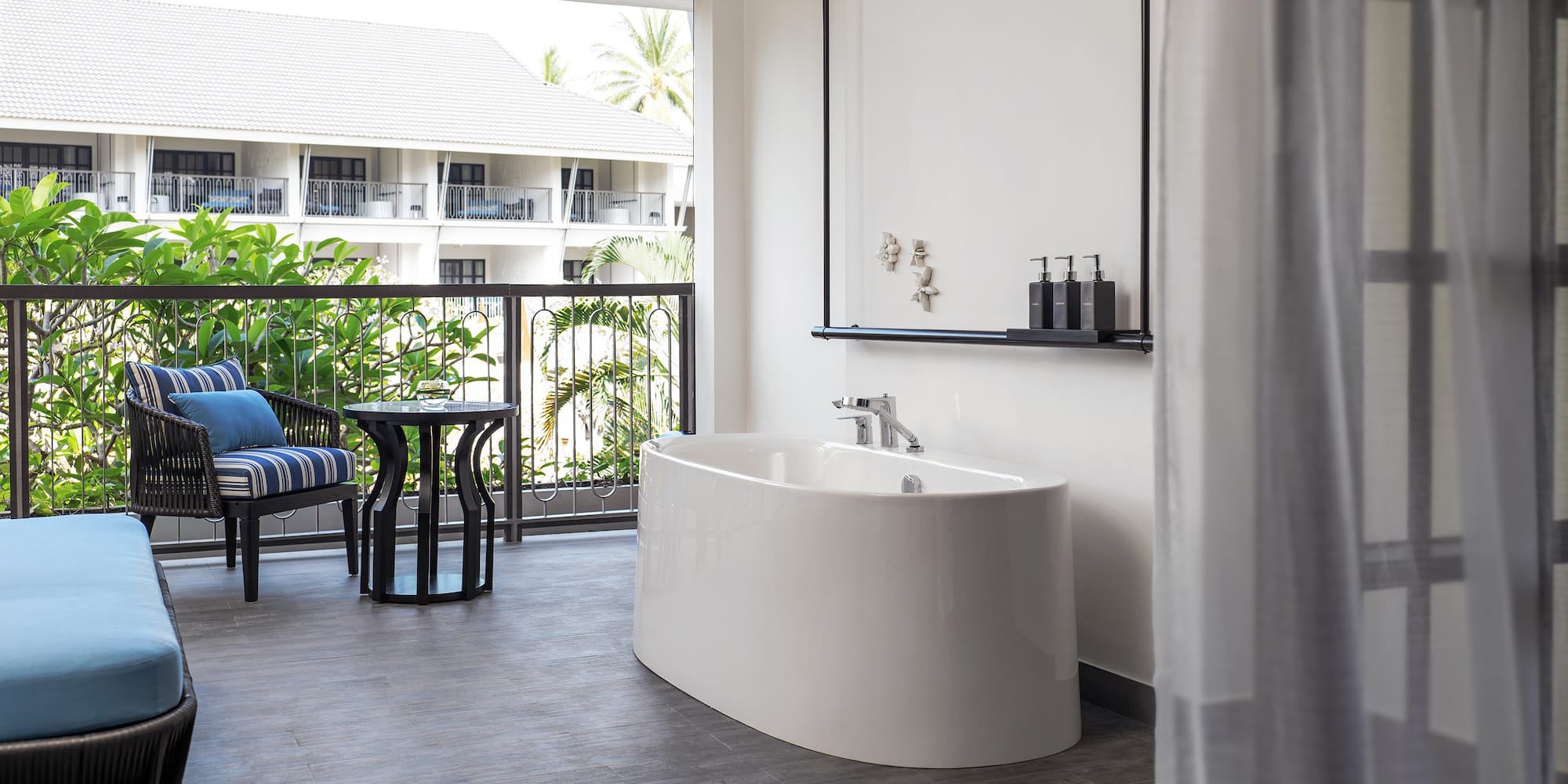 a white bathtub in a room with a balcony and a window