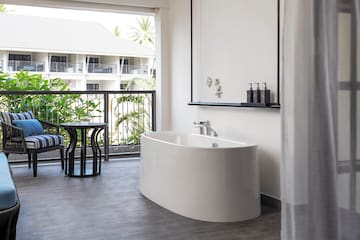 a white bathtub in a room with a balcony and a window