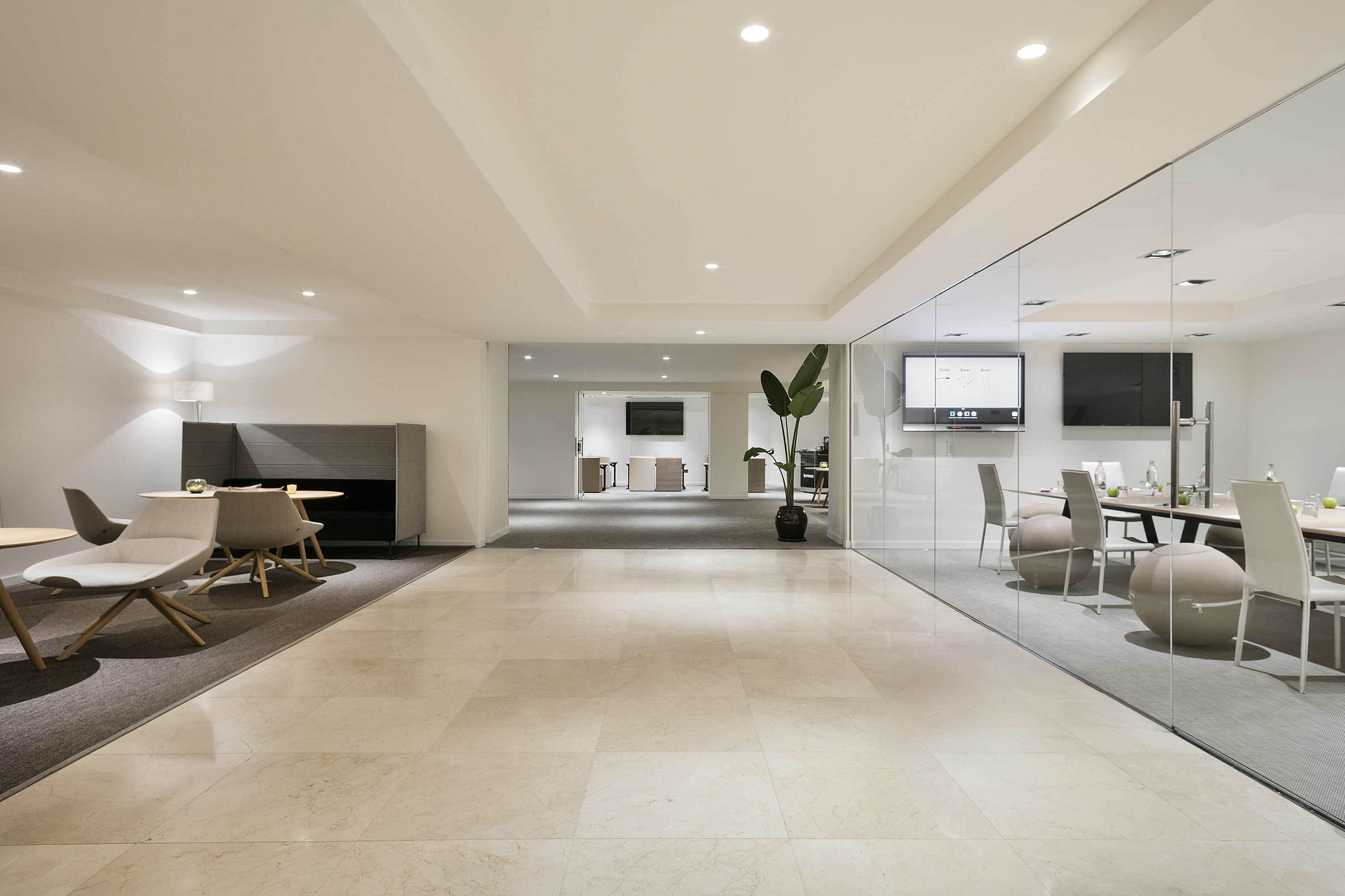 Modern office with glass meeting room, lounge area, and polished marble floors.
