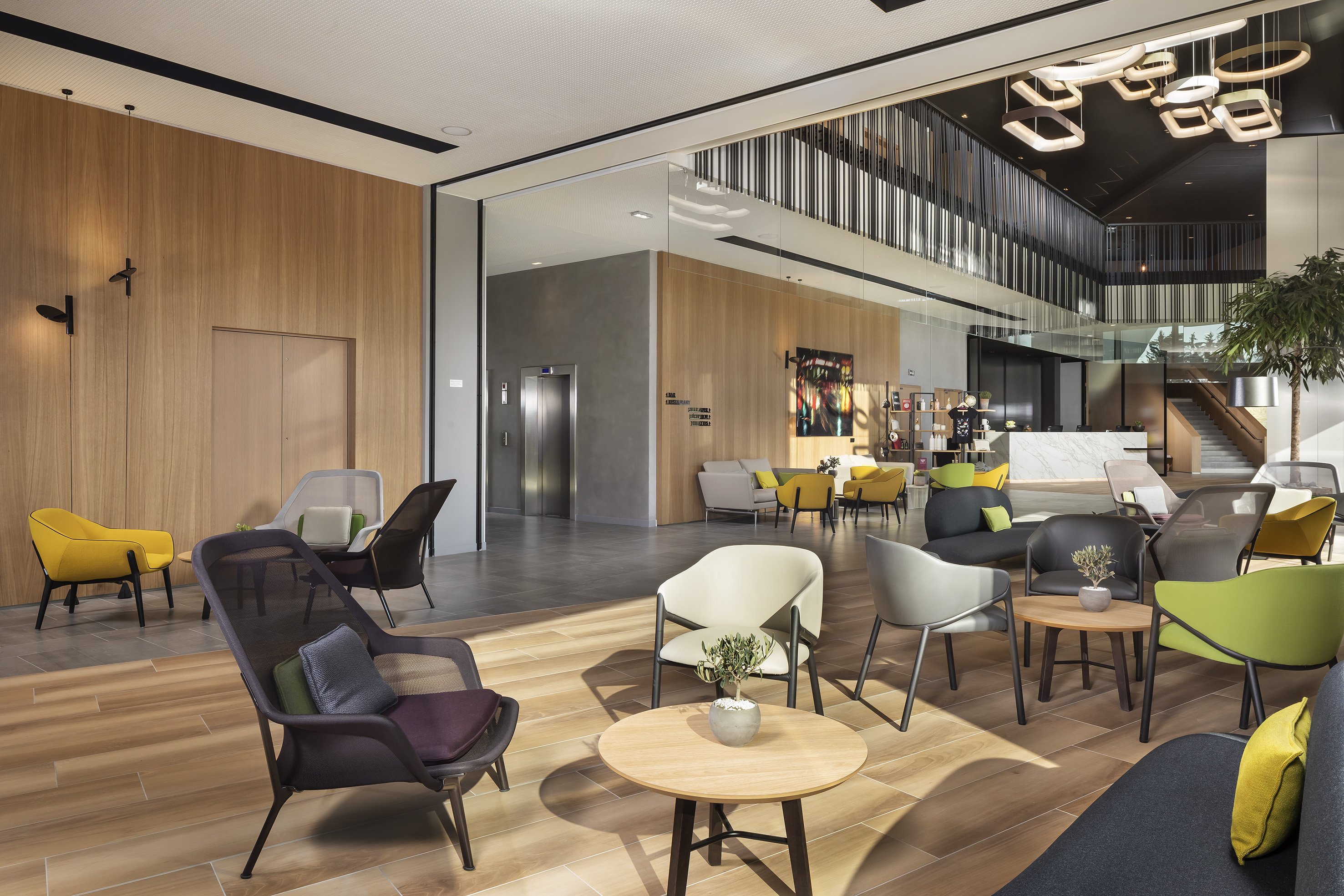 Modern hotel lobby lounge with colorful chairs, wood panels, and contemporary lights.