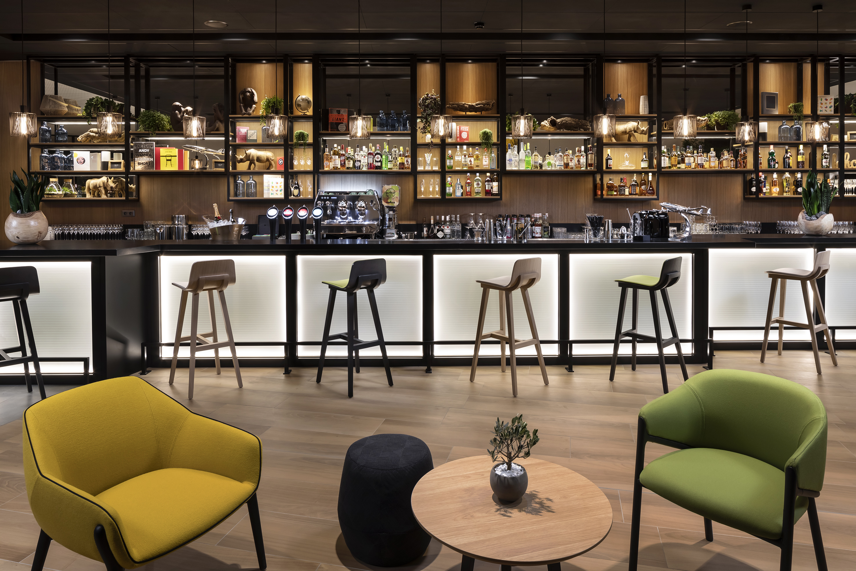 Upscale hotel bar with illuminated counter, liquor shelves, and modern lounge seating.