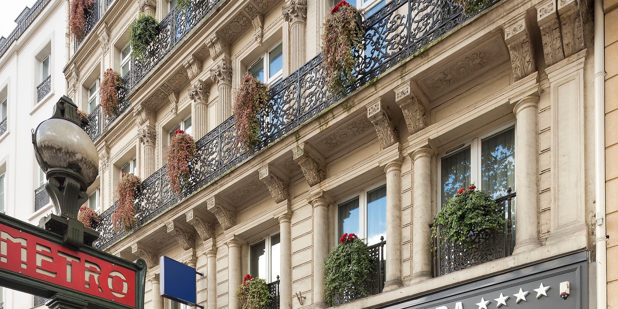 a building with a sign and plants on the balcony