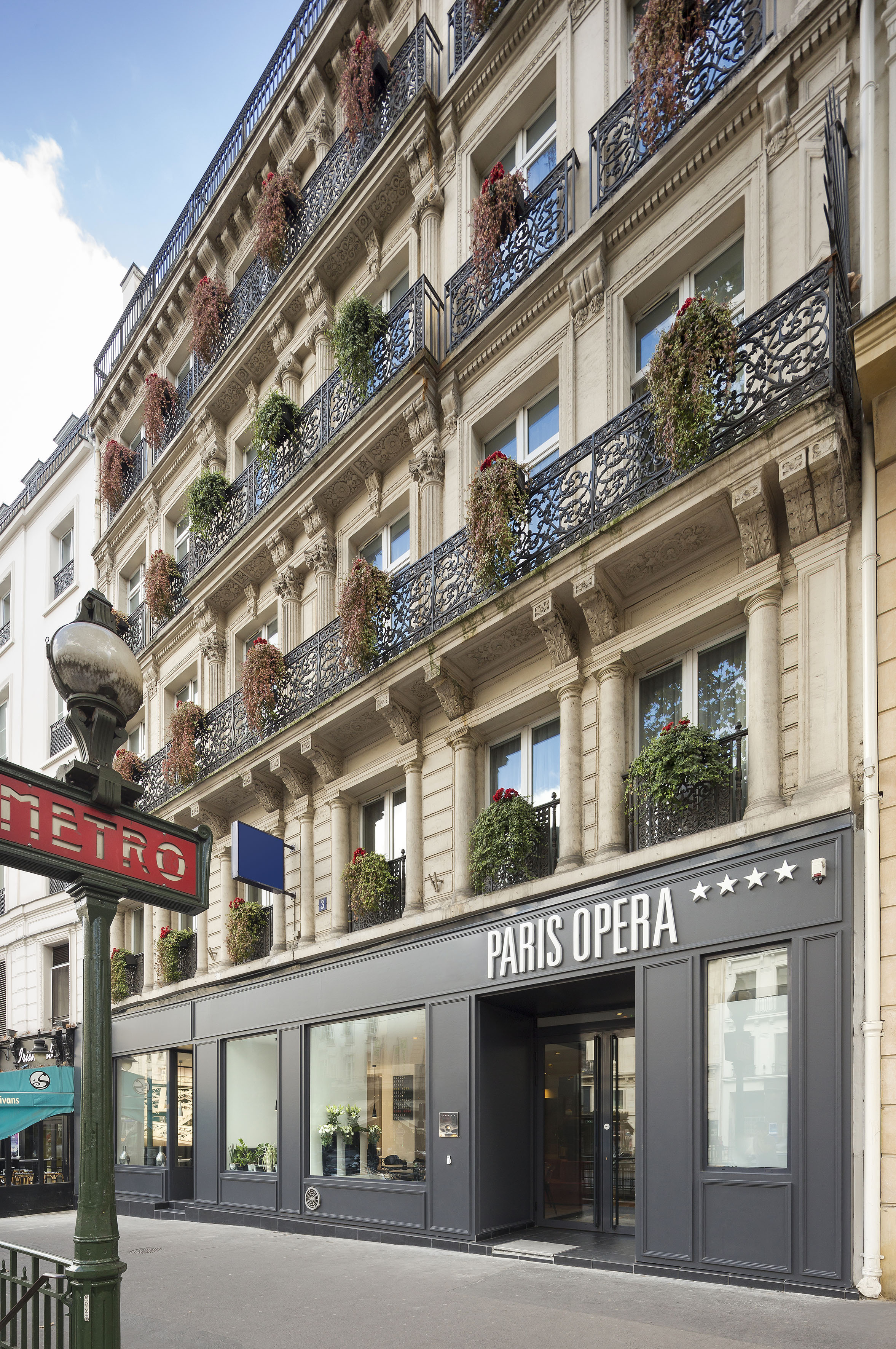 a building with a sign and plants on the balcony