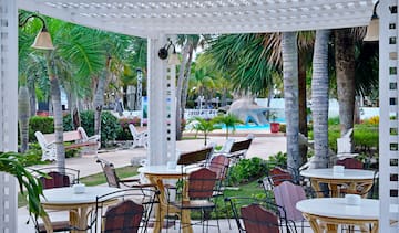 a white pergola with tables and chairs in a resort