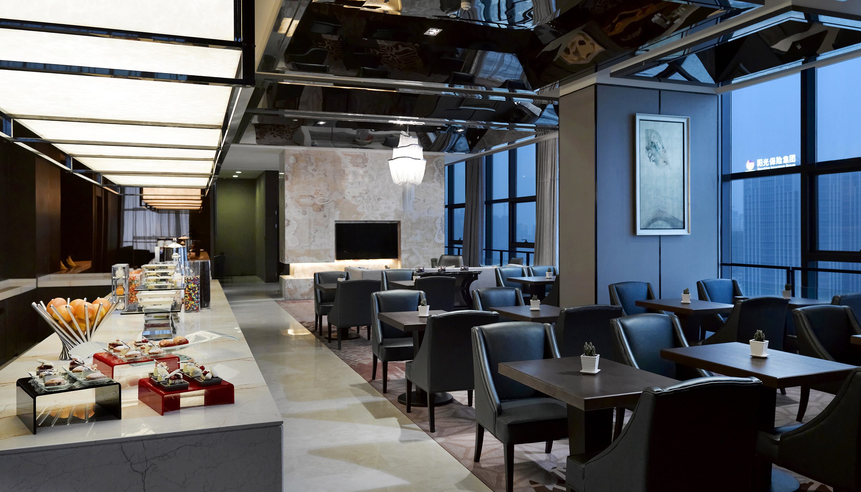 Modern luxury hotel lounge featuring buffet, dining tables, and cityscape views.