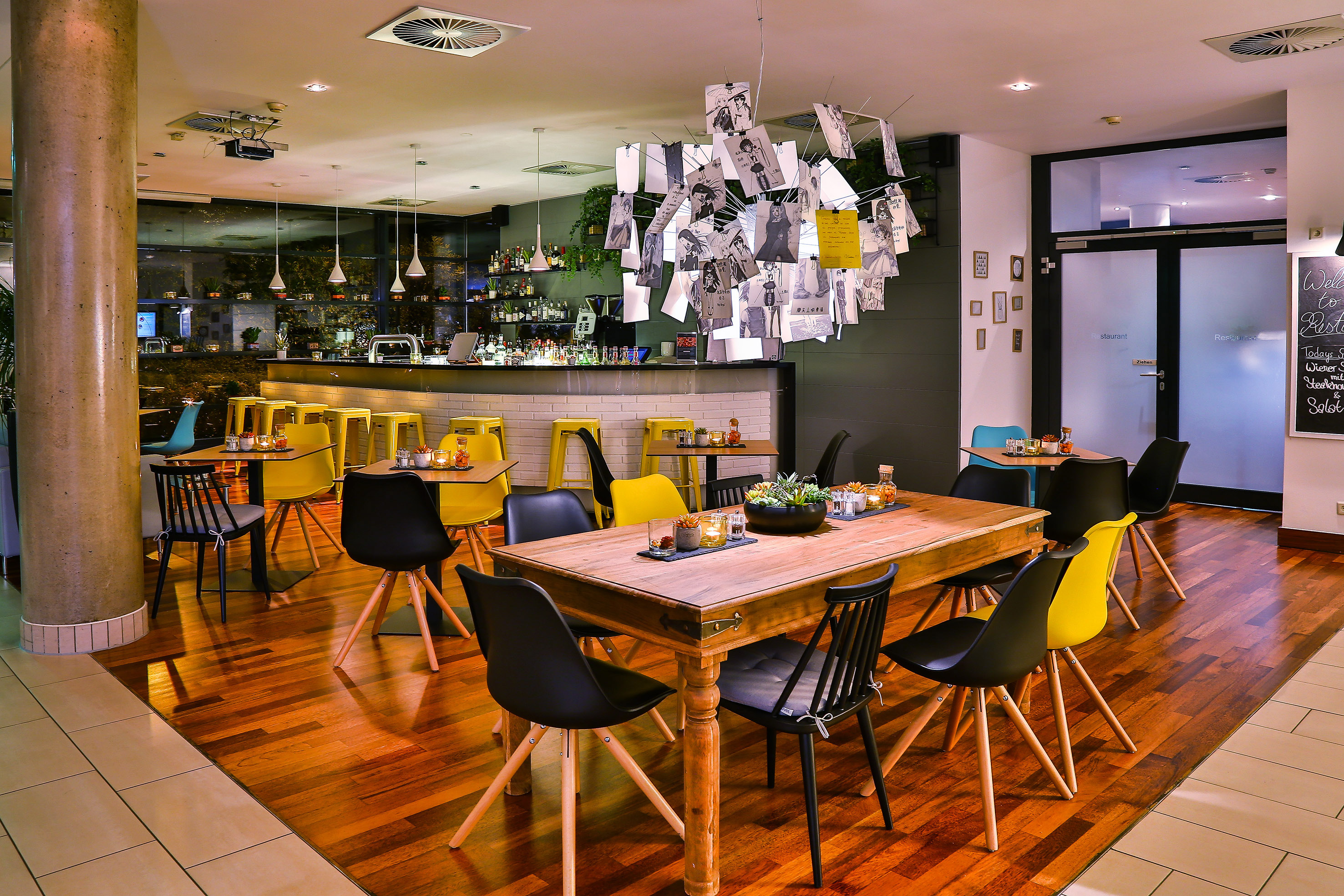 Modern restaurant interior: bar, yellow stools, wooden tables, unique photo chandelier.