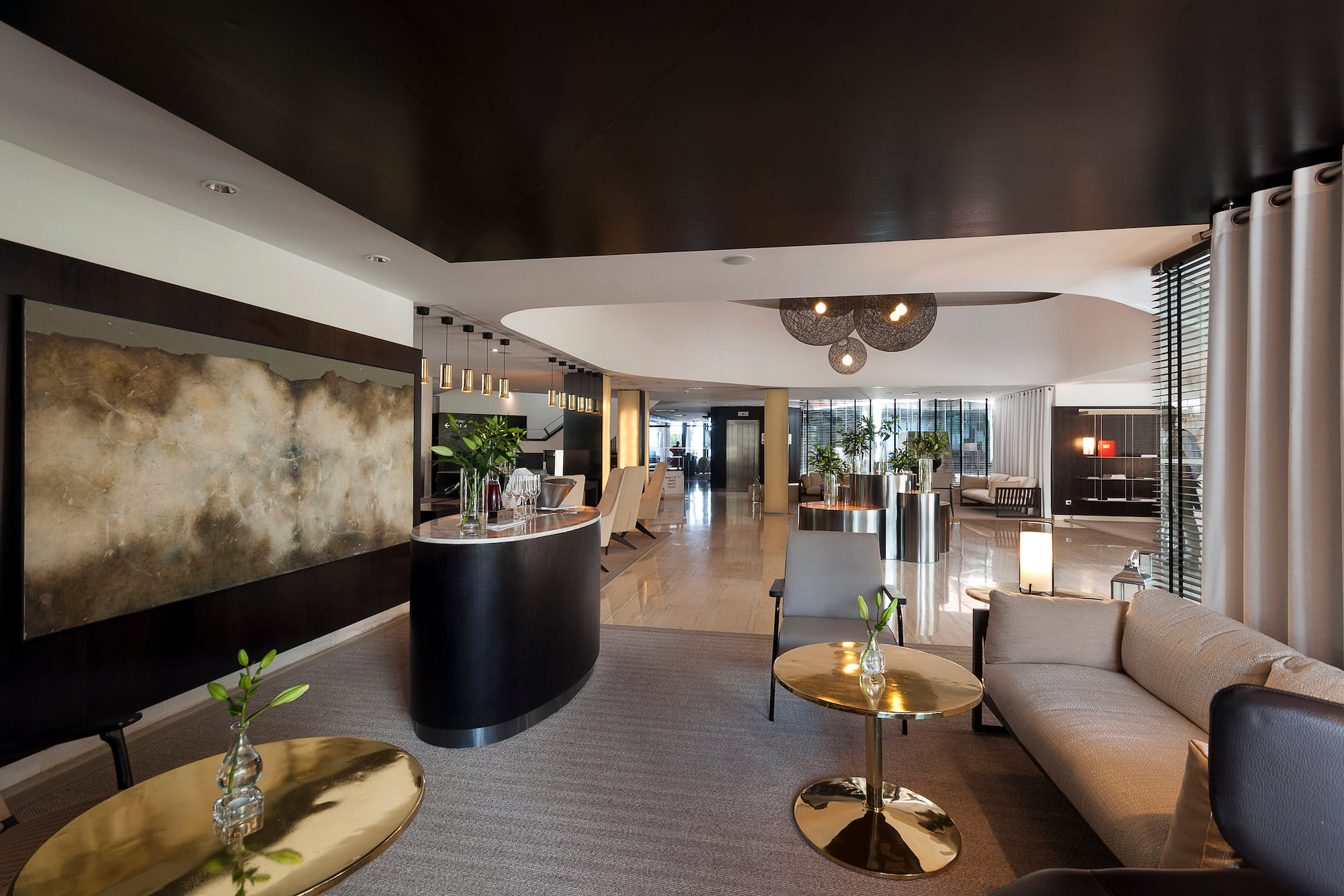 Elegant hotel lobby with modern reception desk, lounge seating, and abstract art.