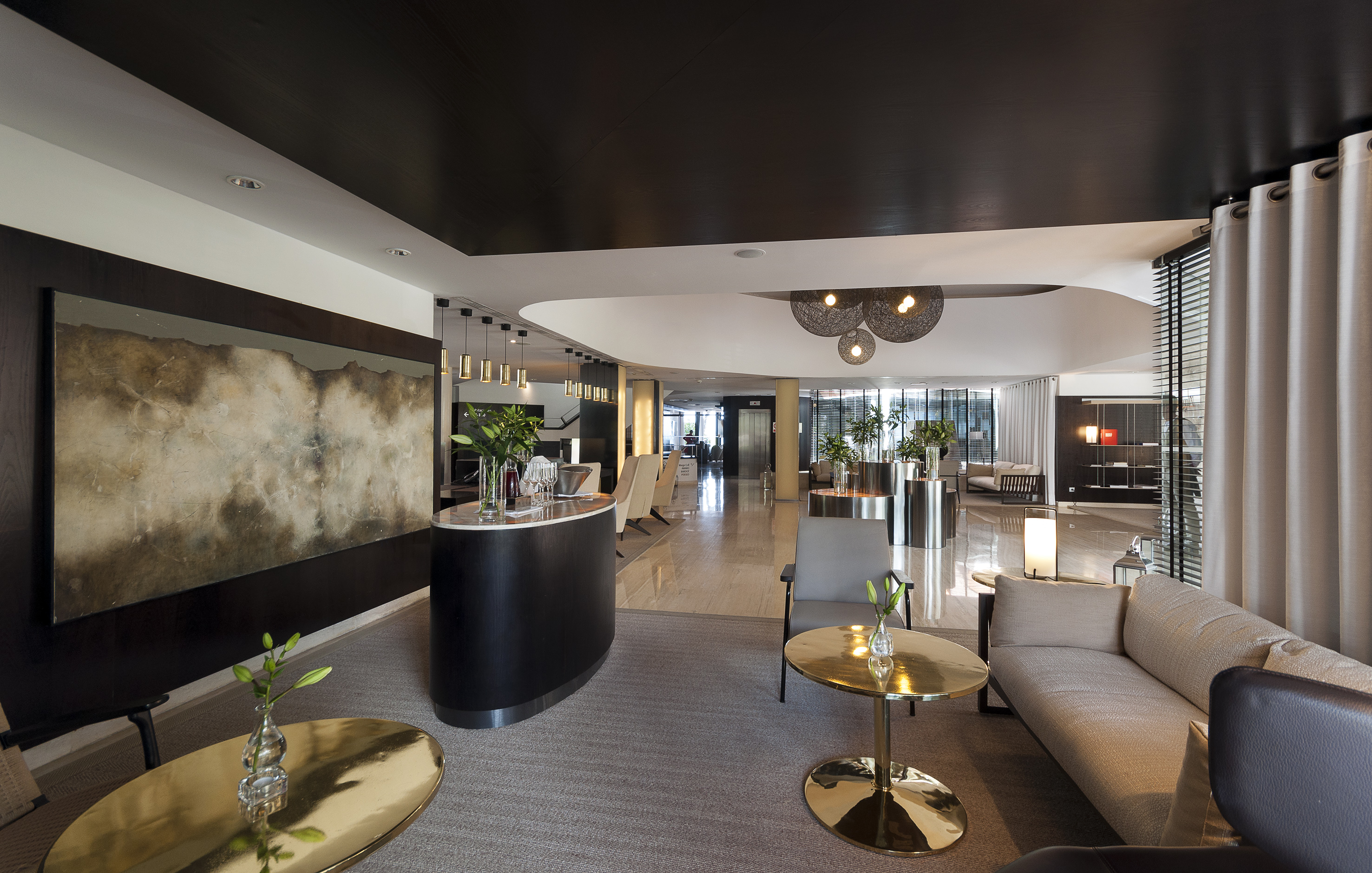 Elegant hotel lobby with modern reception desk, lounge seating, and abstract art.