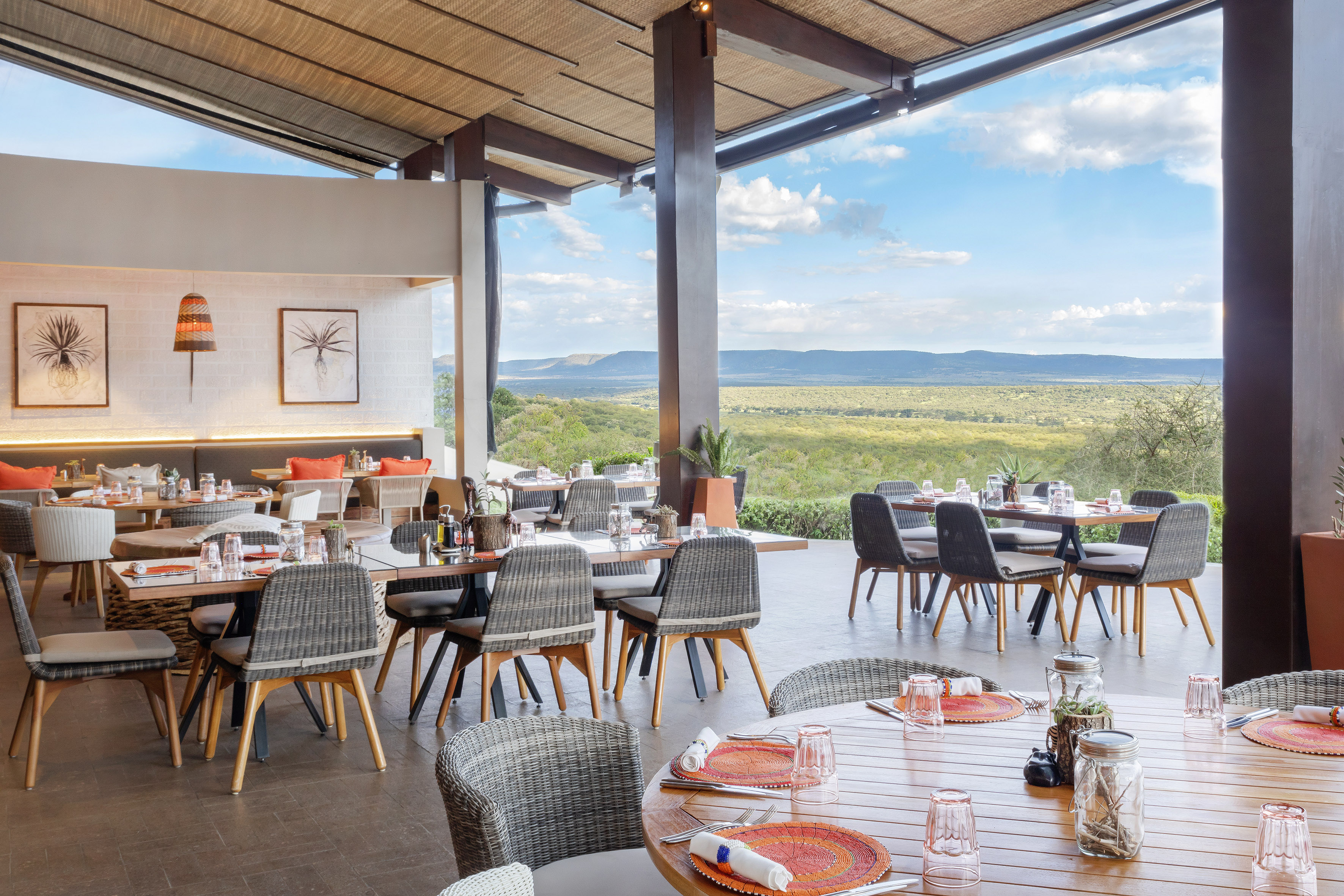 Open-concept restaurant with natural decor, set tables, and a vast valley view.