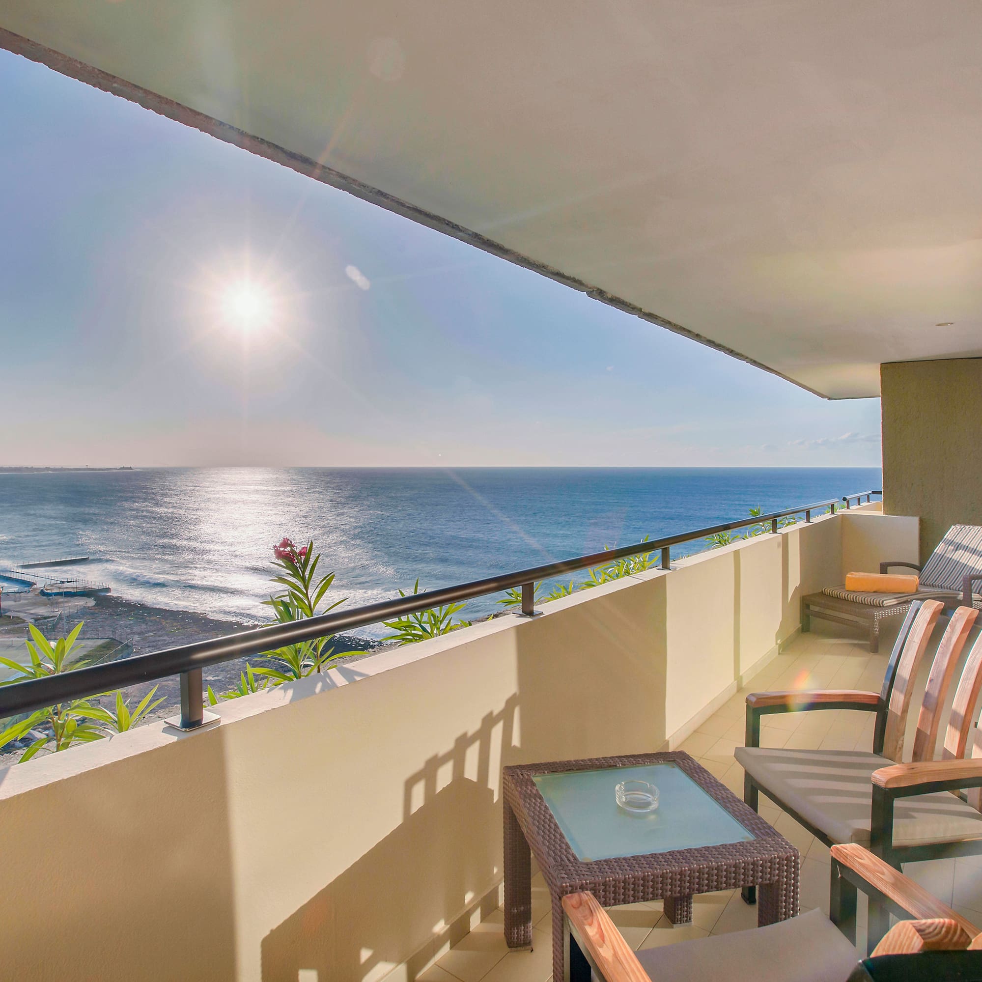 a balcony with chairs and a table overlooking the ocean