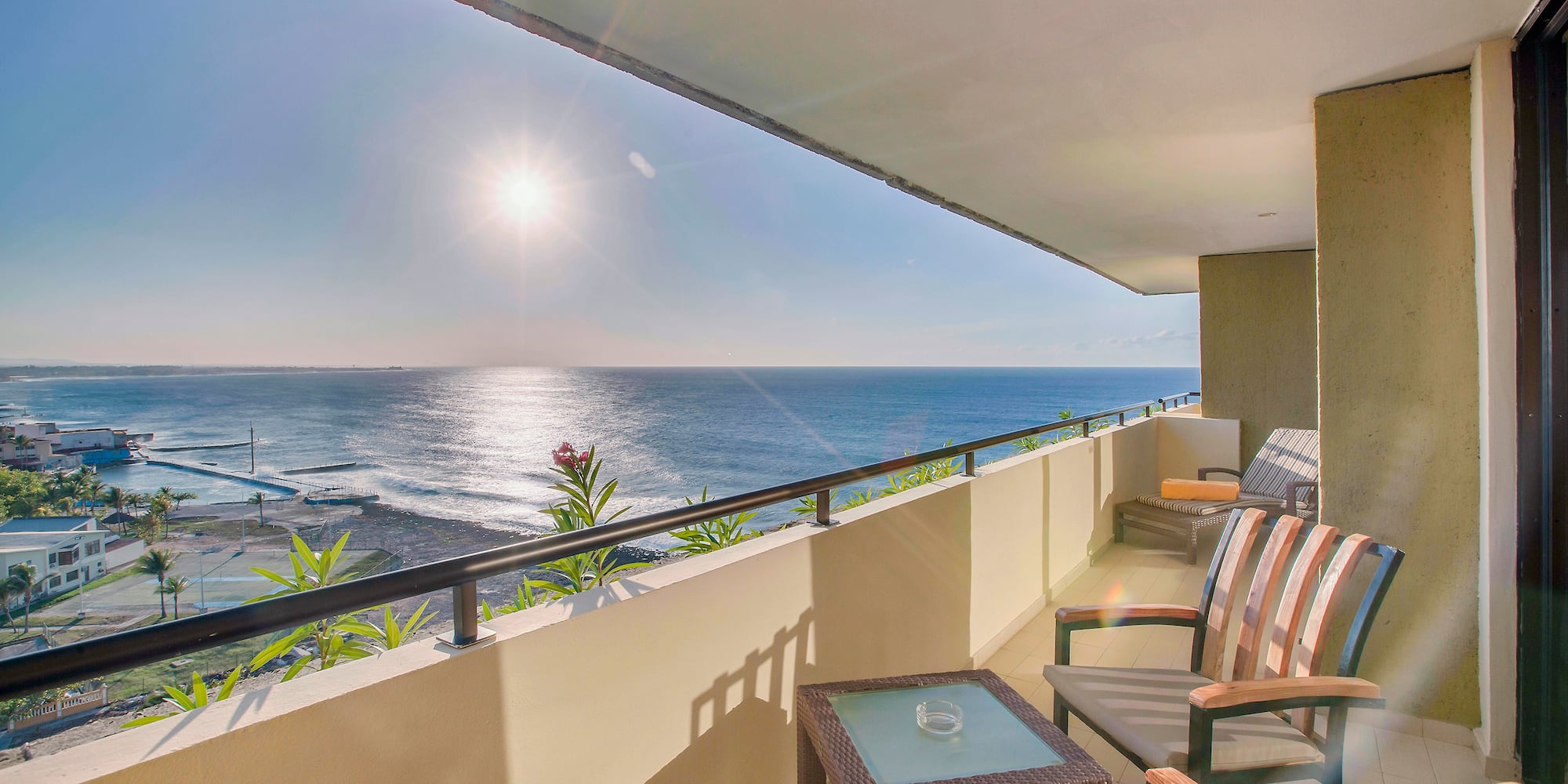 a balcony with chairs and a table overlooking the ocean