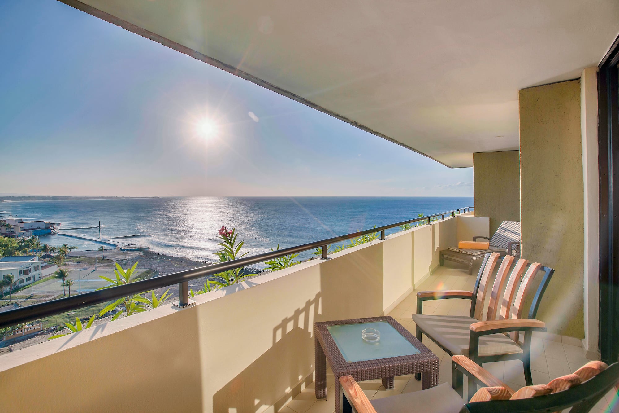a balcony with chairs and a table overlooking the ocean