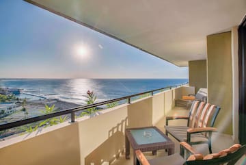 a balcony with chairs and a table overlooking the ocean