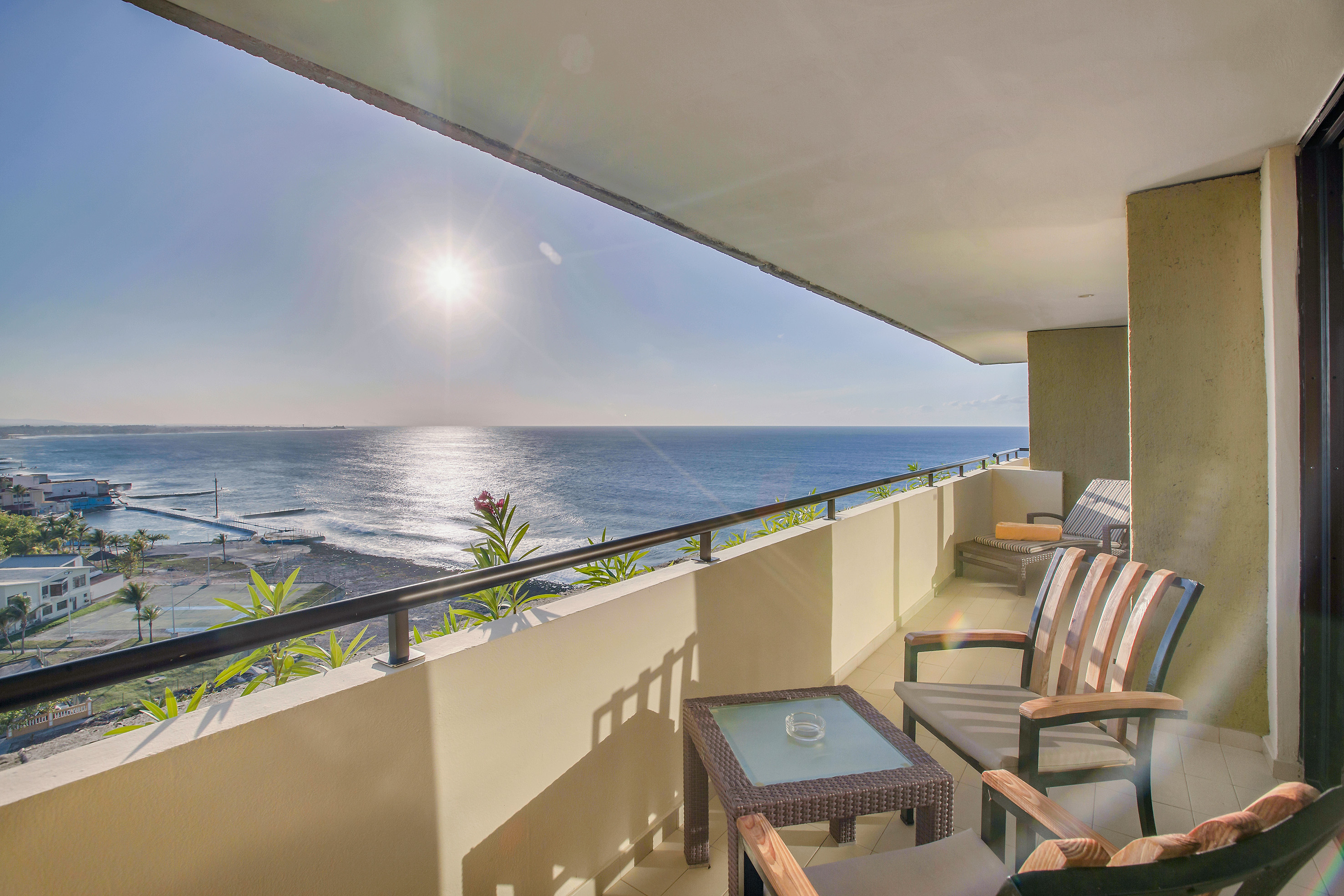 a balcony with chairs and a table overlooking the ocean